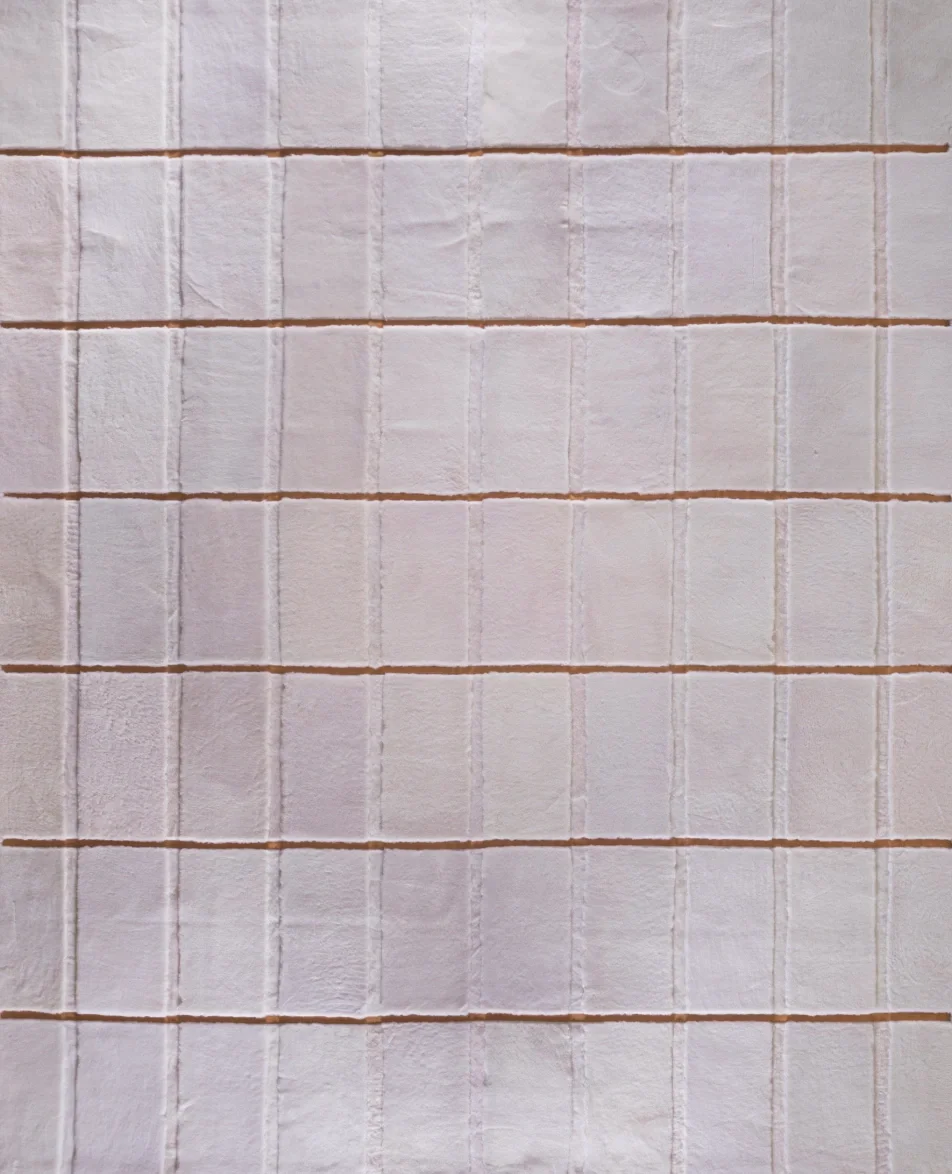 Several white rectangular tiles with textured surface and horizontal grout lines, arranged in a grid pattern.