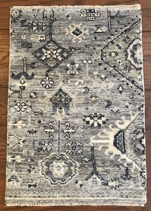 Gray and beige patterned area rug with floral and geometric designs, placed on a wooden floor.