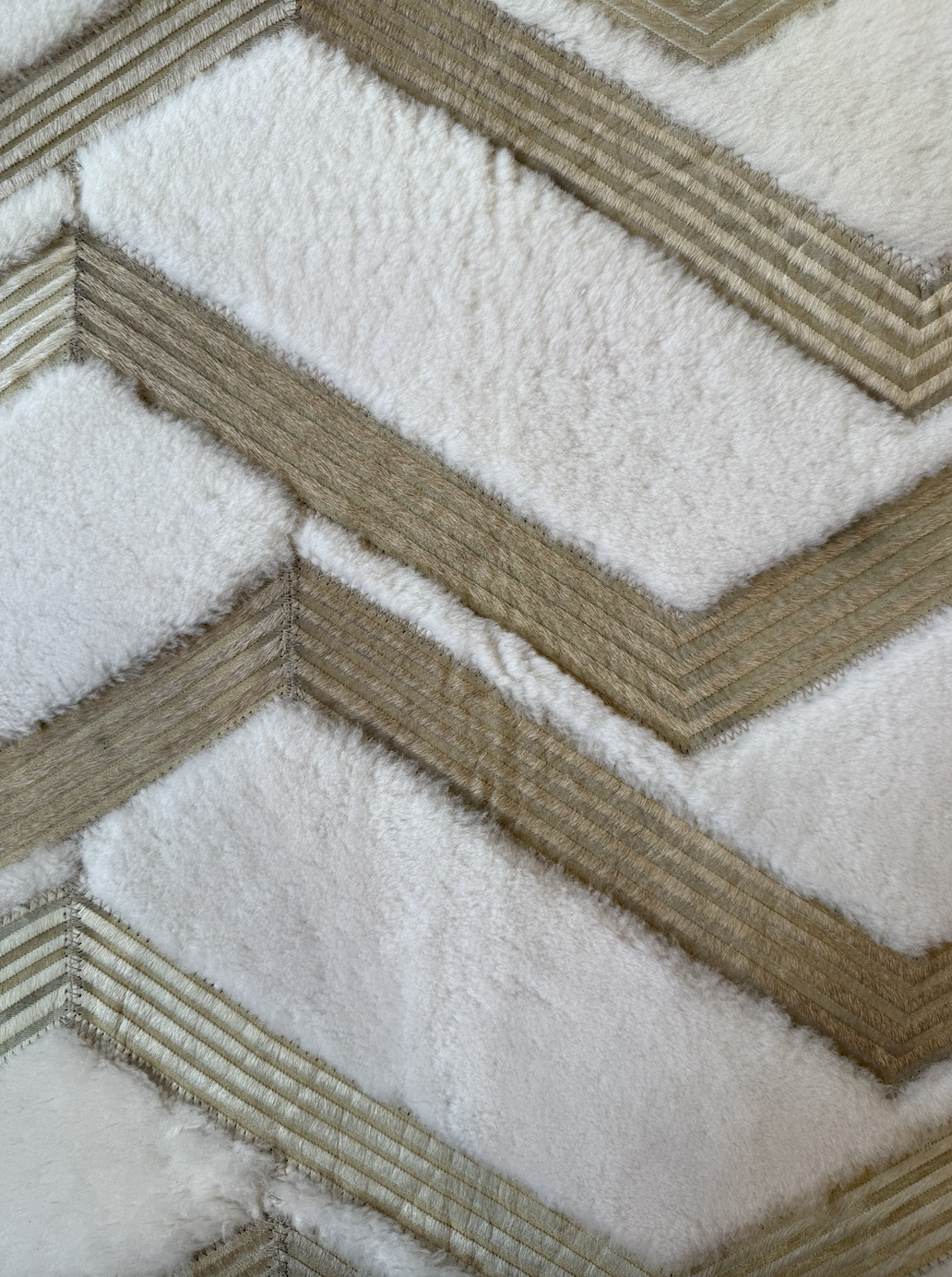 Close-up of a layered, checkerboard-patterned carpet with alternating beige and white textured sections.