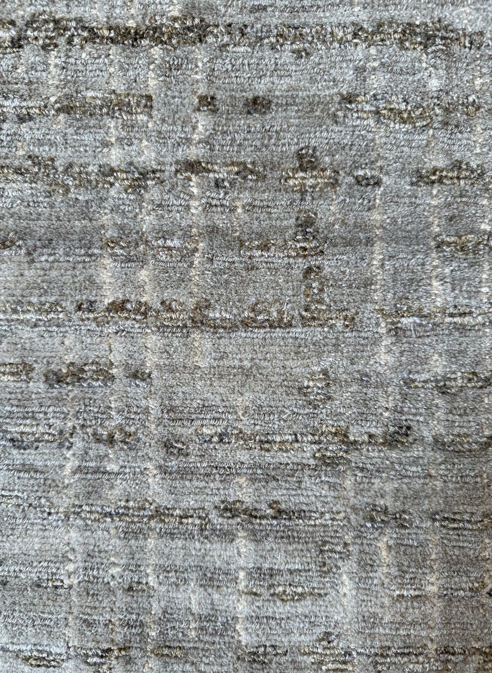 Close-up of a textured beige and gray patterned carpet.