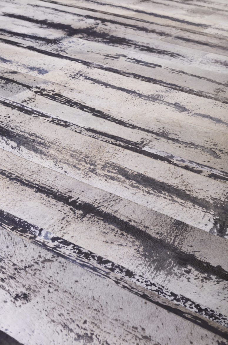 Close-up of a weathered, distressed wooden surface with streaks of white, black, and gray paint.