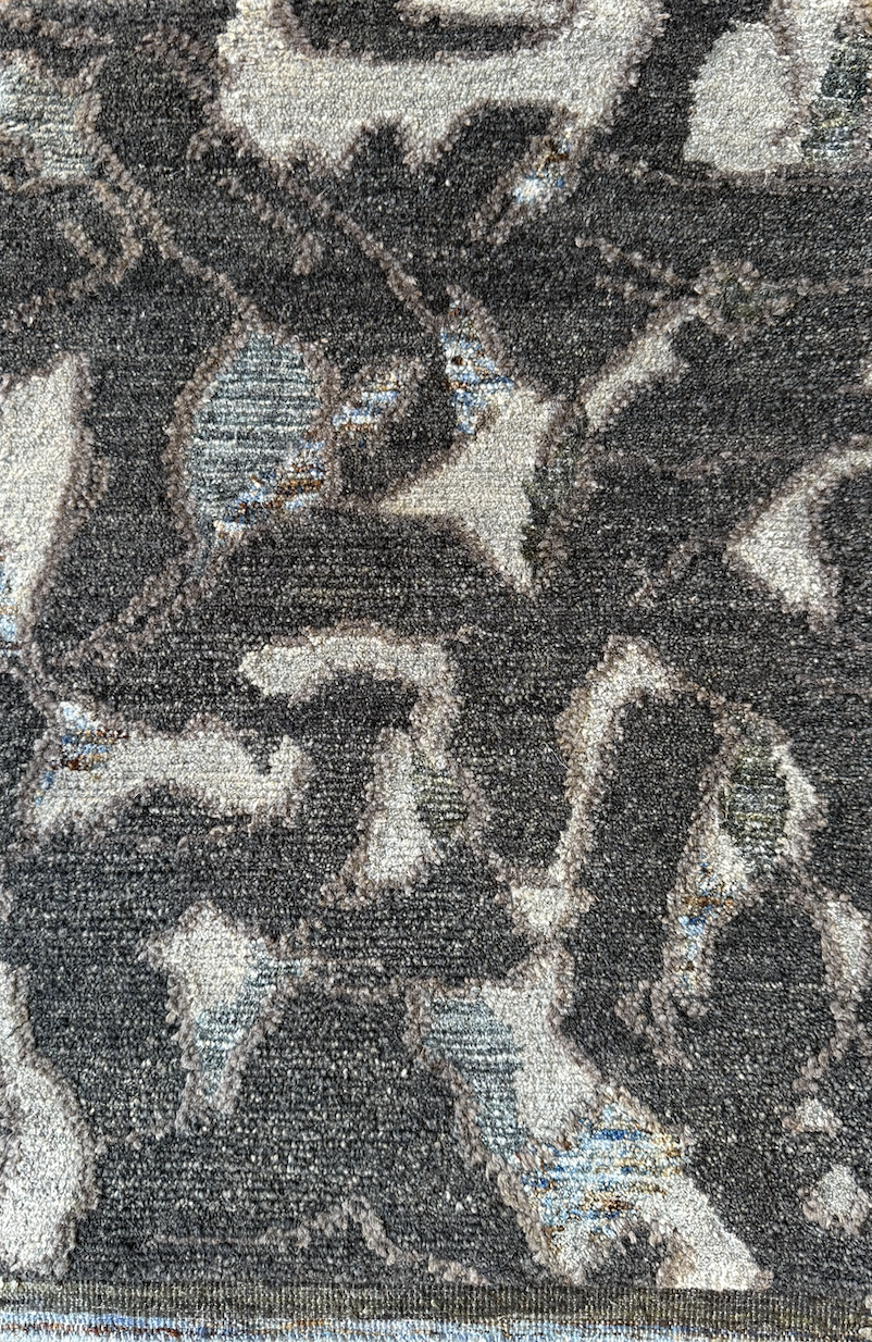 Close-up of a textured carpet with a dark and light abstract pattern.