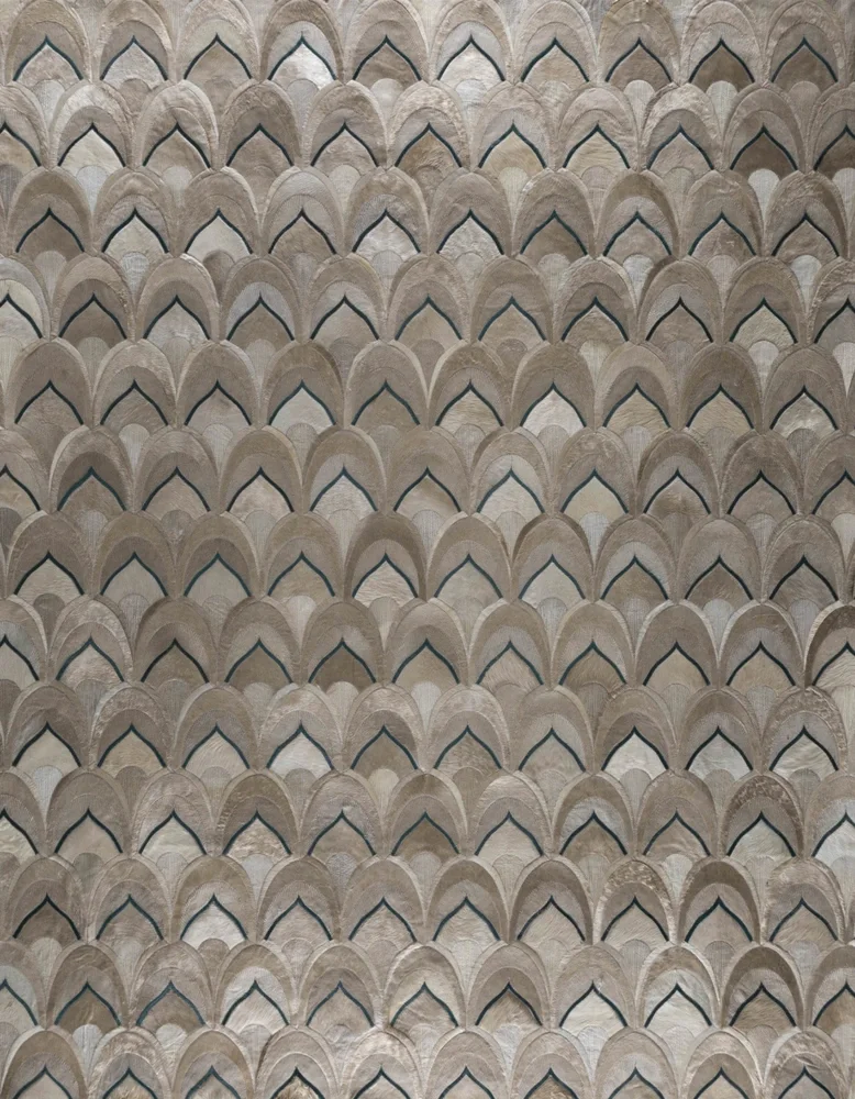 Close-up of a tiled wall with a repeating pattern of overlapping, curved shapes in beige and cream tones, outlined in black.