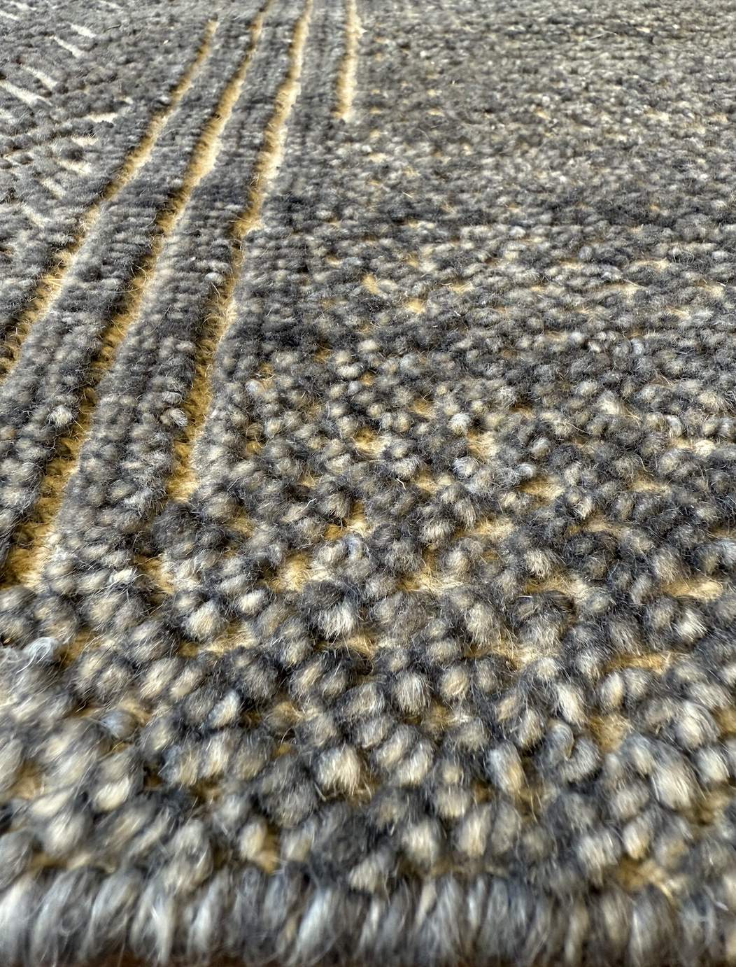 Close-up of a textured gray and beige woven textile with parallel yarns and a mixed, speckled pattern.