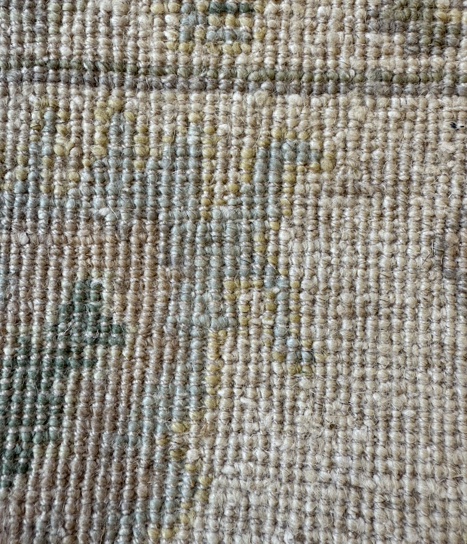 Close-up of a woven, textured beige and green carpet.