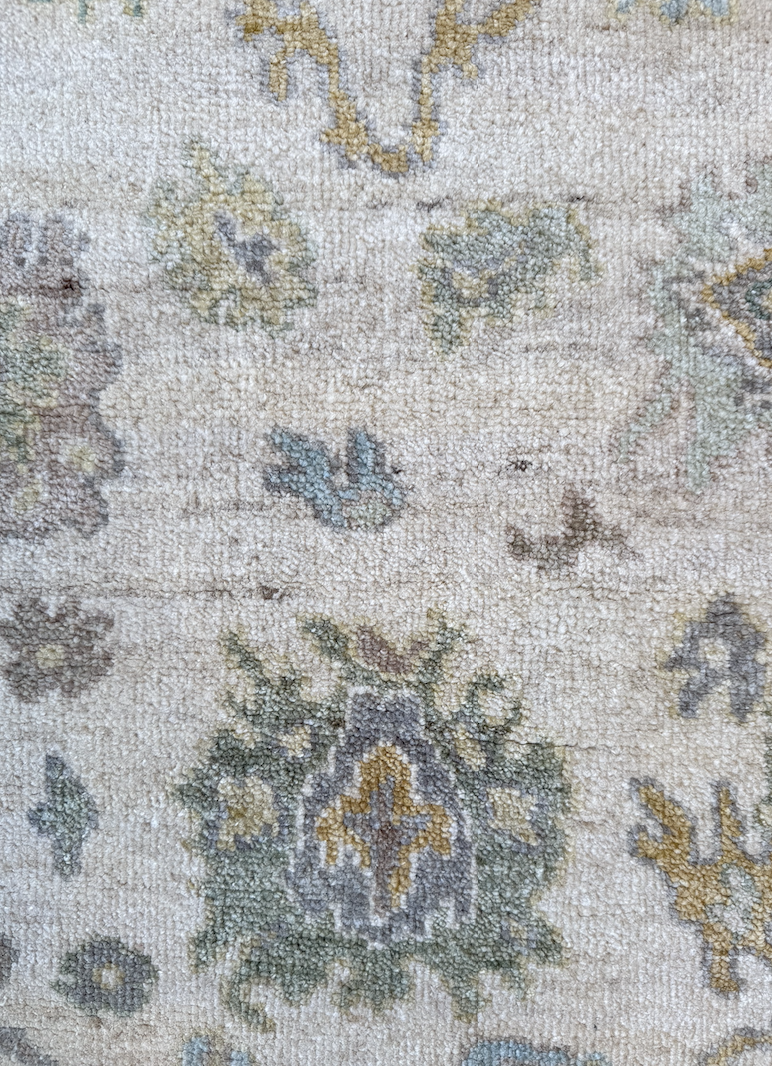 A close-up of a patterned, woven carpet with floral and geometric designs in muted colors.