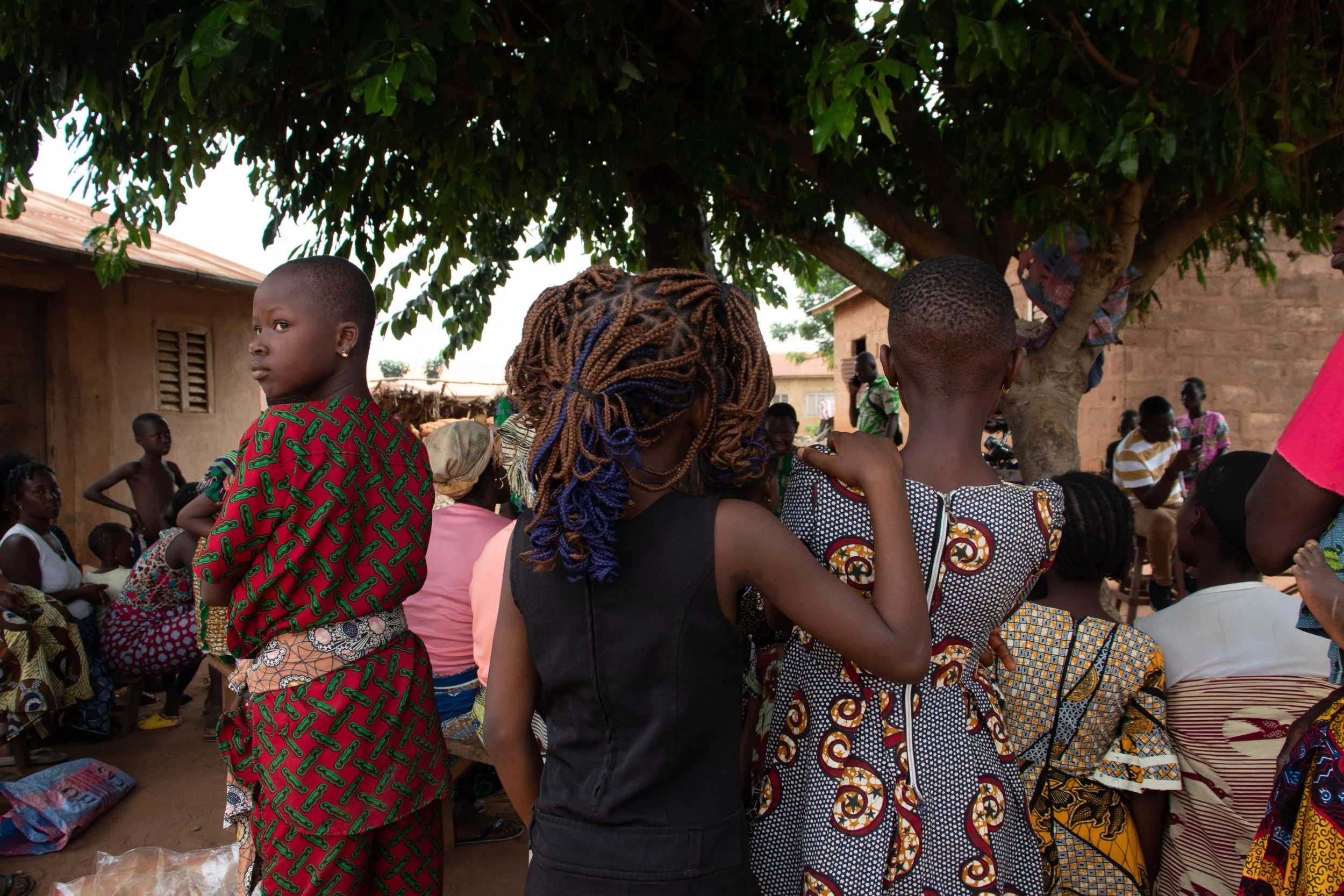 Three younger girls are standing in the back and observing the meeting, August 2024.