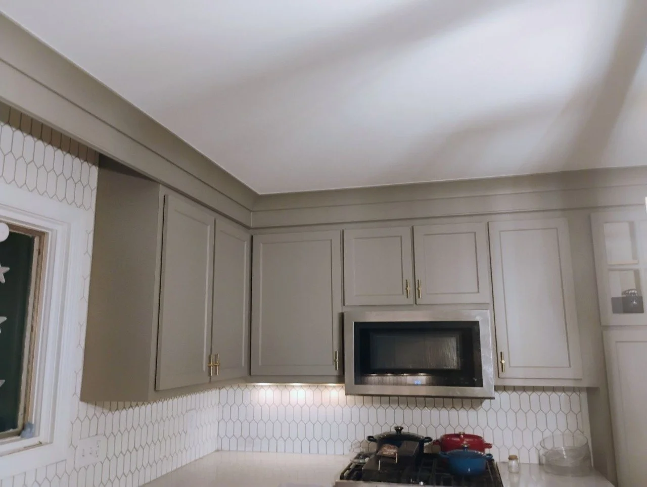 Kitchen with beige cabinets, a black microwave above the stove, and a white hexagon tile backsplash.