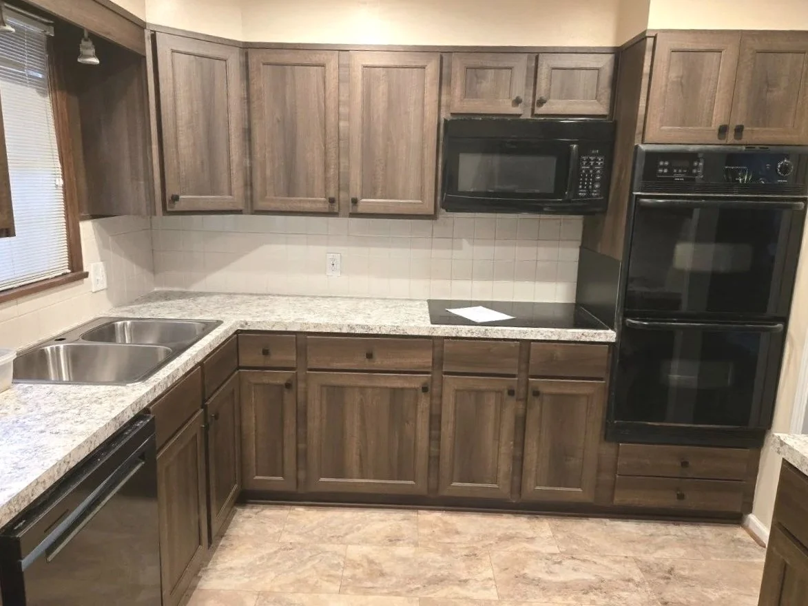 Kitchen with wooden cabinets, granite countertops, a double sink, a microwave, and a double oven.