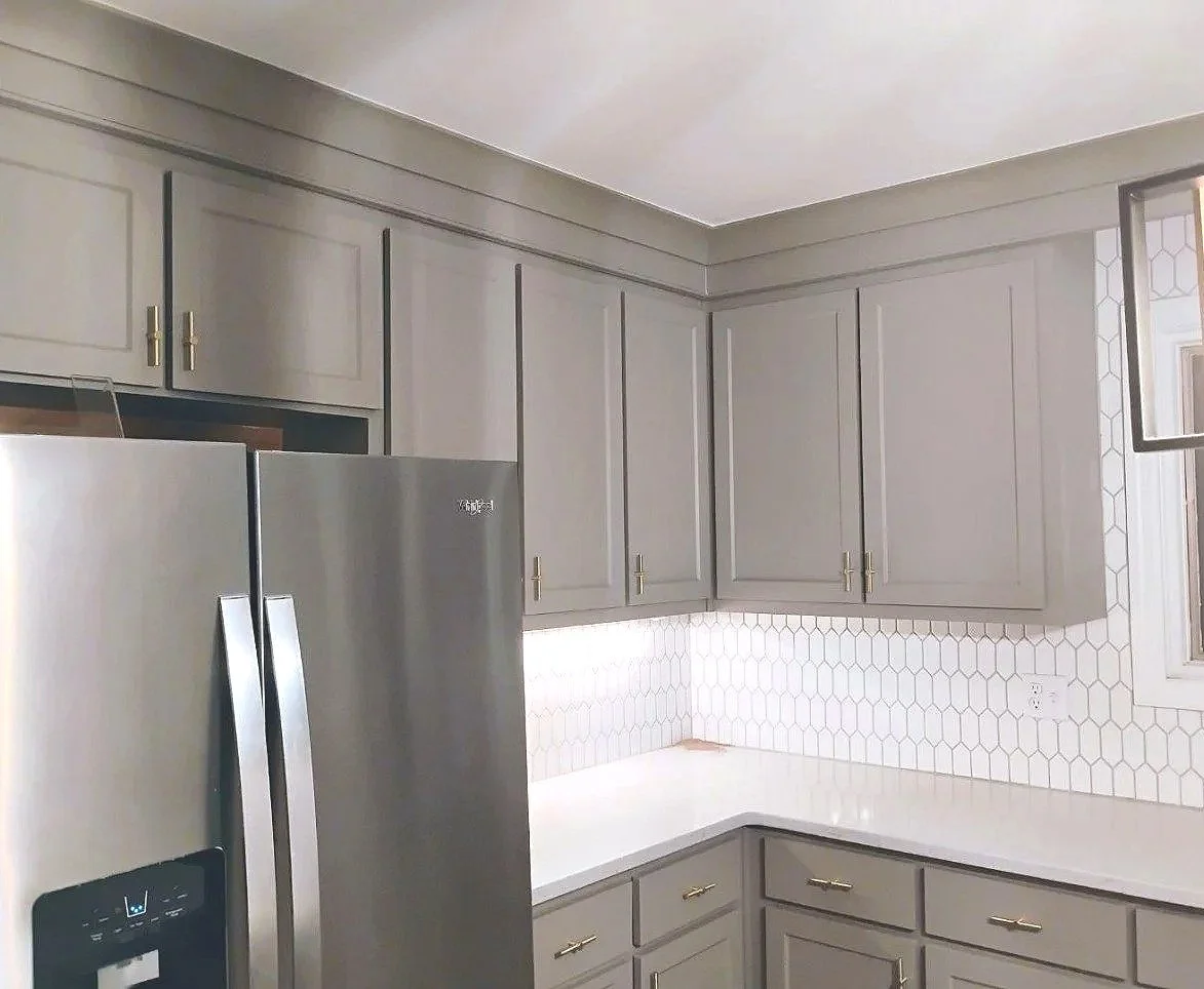 Kitchen with gray cabinets, white countertops, a stainless steel refrigerator, and a white hexagon tile backsplash.