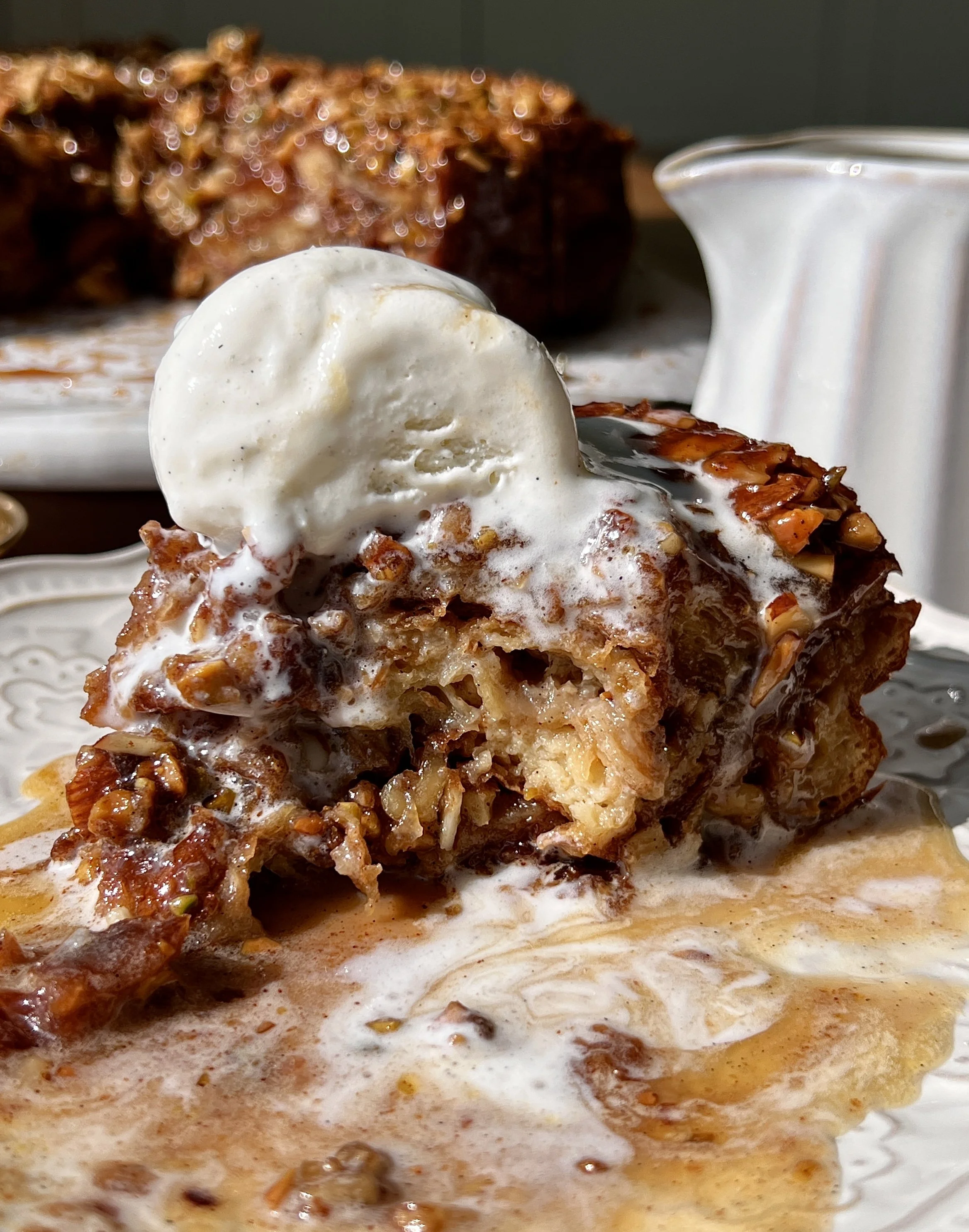Golden baklava croissant bread pudding made with buttery flaky croissants and vanilla bean custard swirled with a warm gooey baklava filling served warm with a scoop of vanilla ice cream, honey buttermilk syrup, and flaky sea salt.