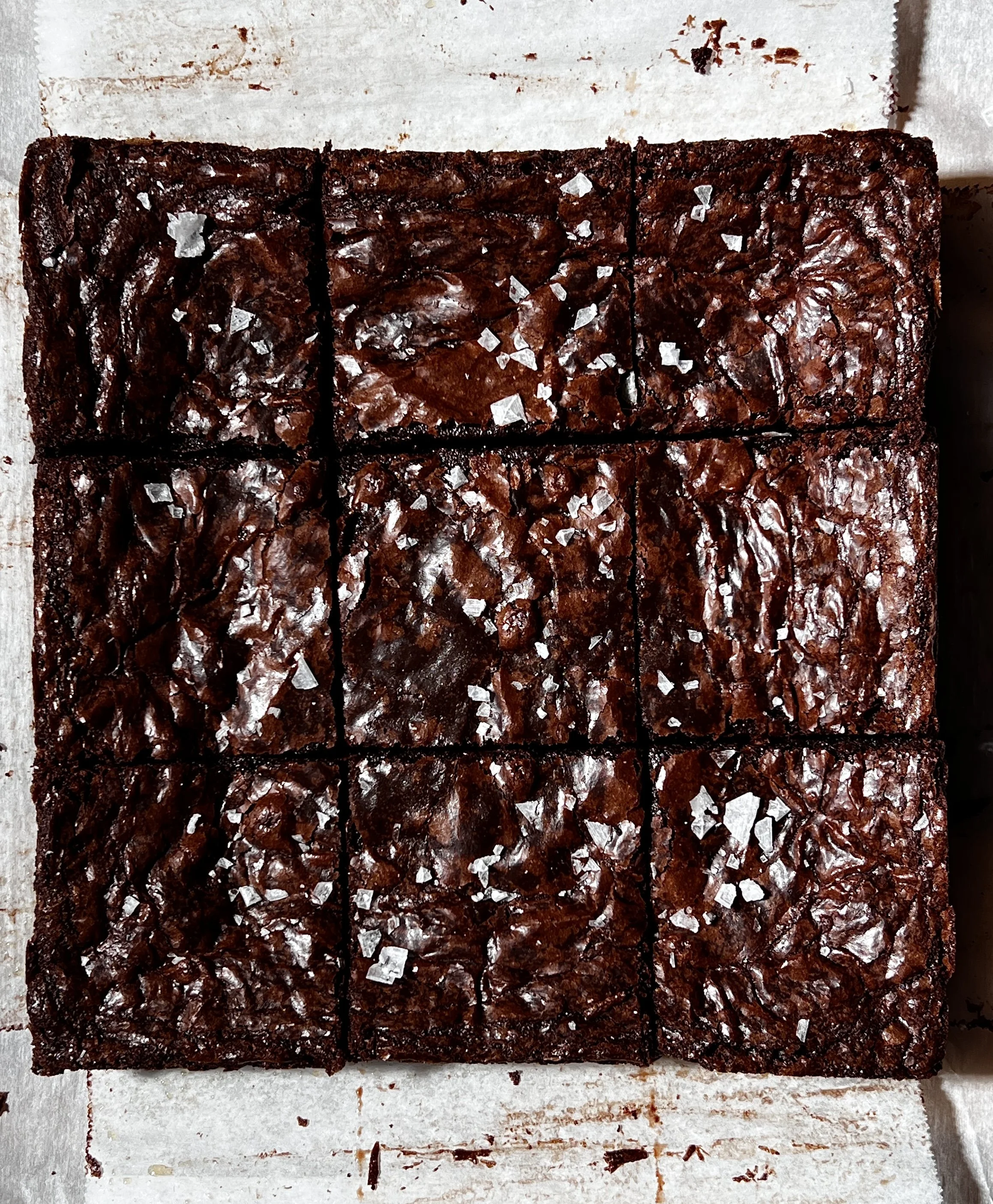 Fudgy crinkle-top brown butter brownies with a shiny crackled top, melty chocolate chips, and flaky sea salt.