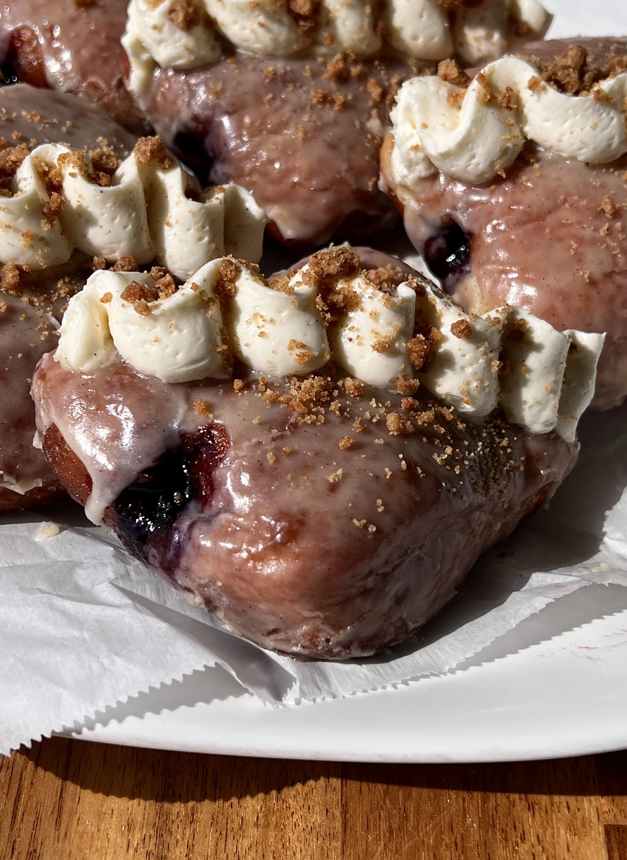Blueberry pie donut bars coated in a silky vanilla bean glaze topped with whipped buttercream and shortbread crumbles served warm with a hot cup of coffee.