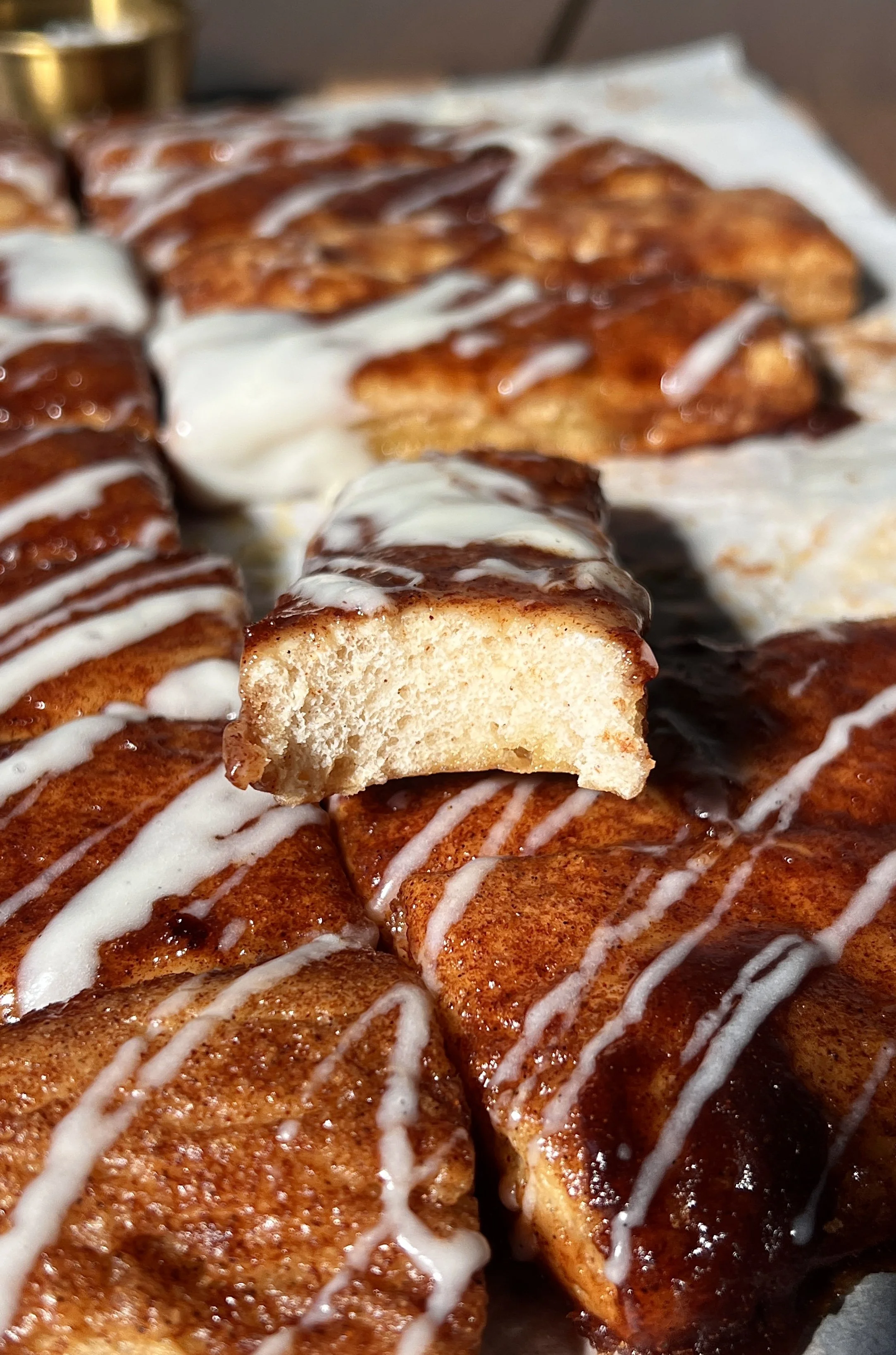 Soft and fluffy sourdough cinnasticks made with sourdough discard and Greek yogurt dough, topped with gooey cinnamon sugar and drizzled with a tangy cream cheese glaze, served warm.