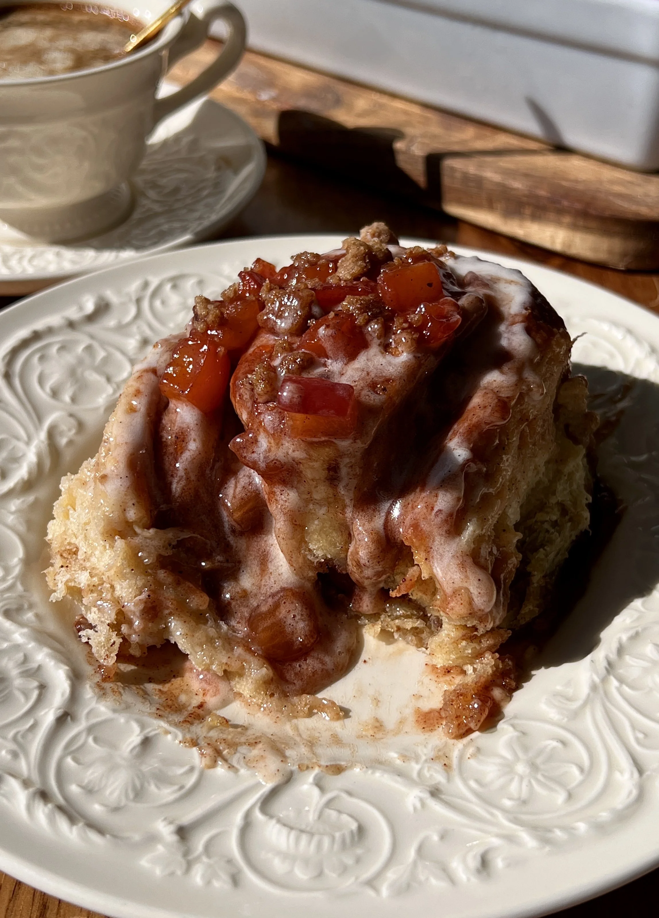 Close-up of a pillowy soft and fluffy peach cobbler cinnamon roll with a gooey brown sugar cinnamon filling and warm spiced homemade peach compote tucked inside every swirl.