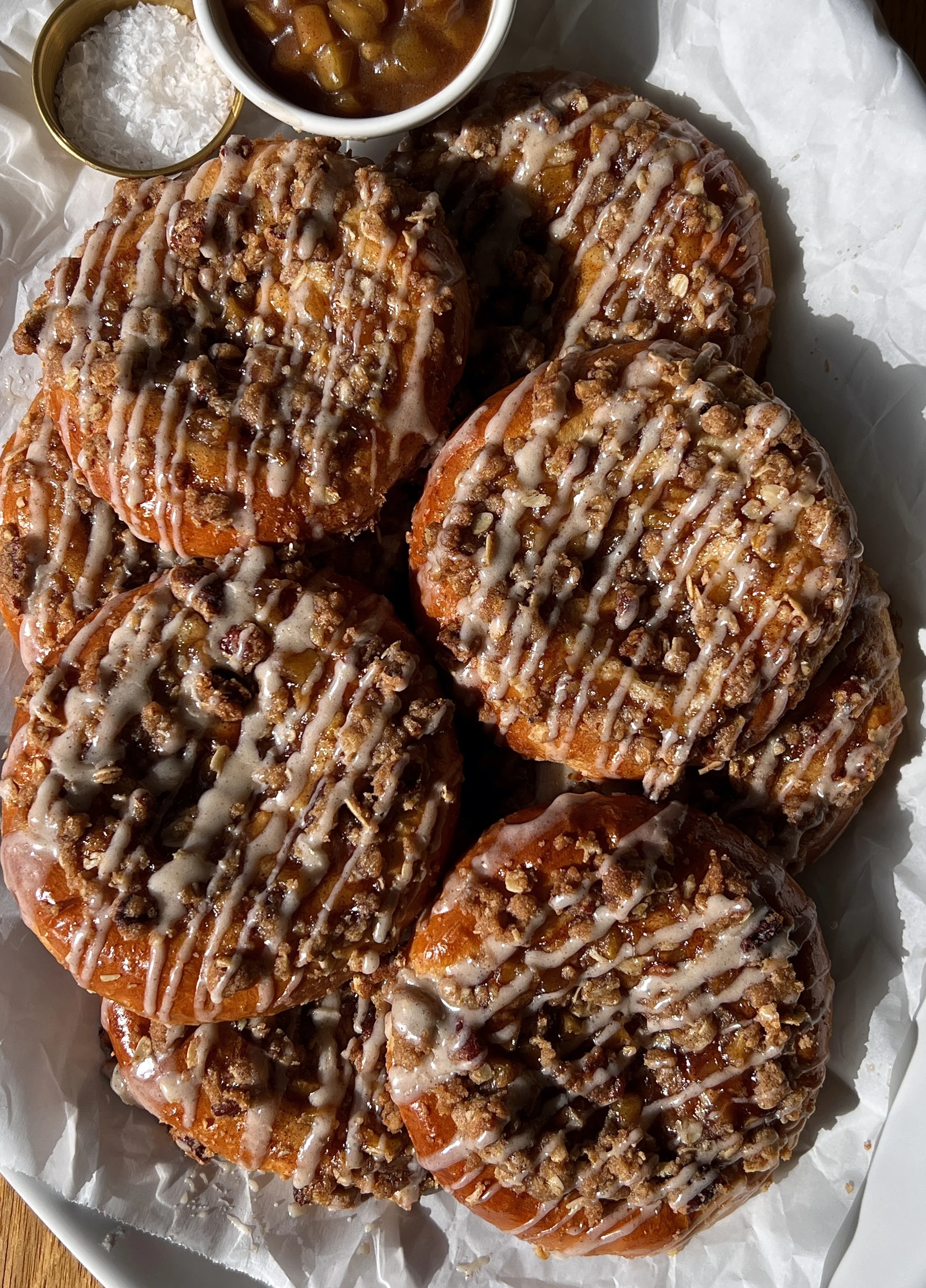 Apple streusel cheesecake buns with a rich and tangy cheesecake filling and warm homemade apple pie filling finished with a pecan oat streusel and maple vanilla bean glaze served warm with a hot cup of coffee.