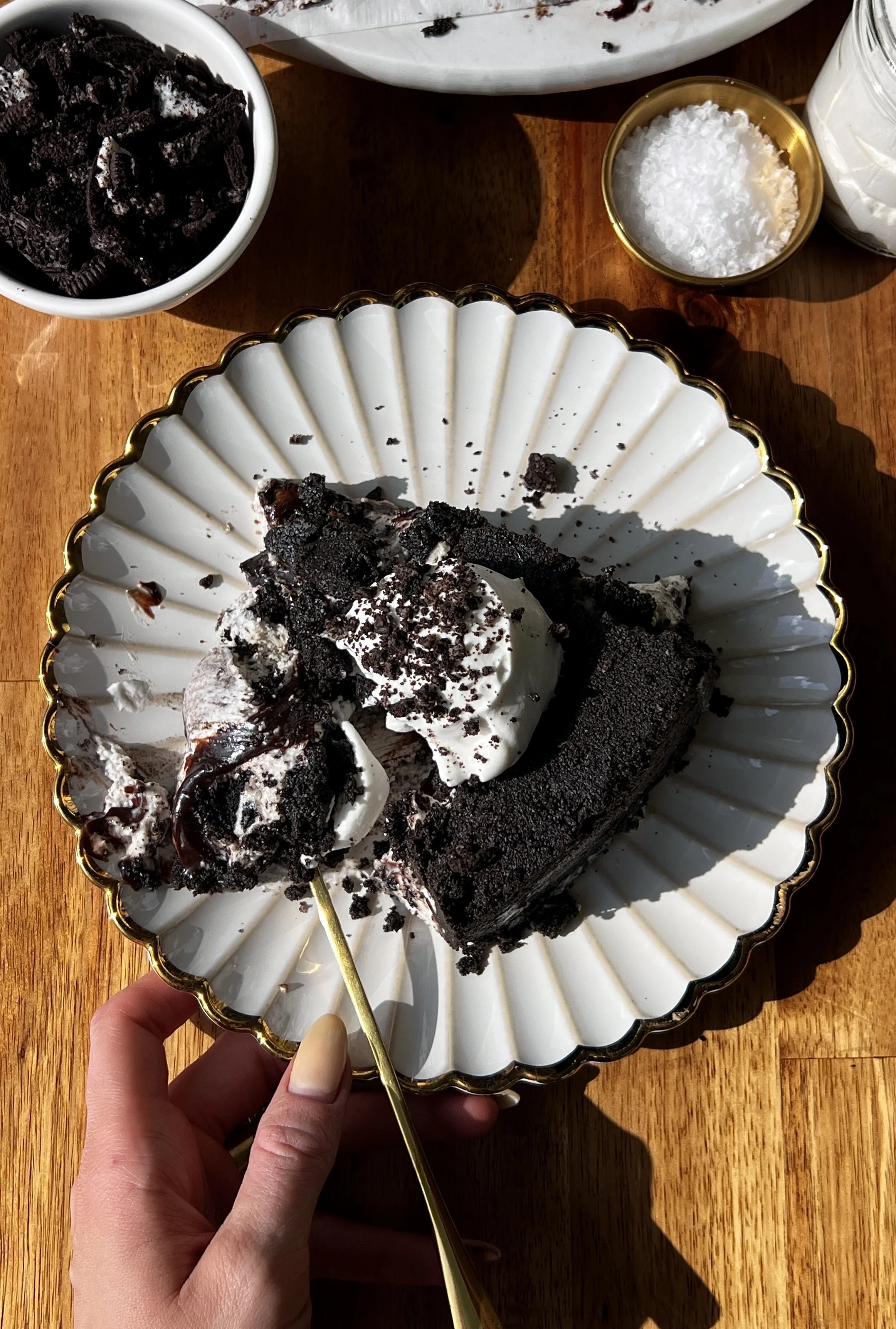 Upside down cookies and cream no-bake cheesecake with a buttery crunchy Oreo cookie crust on top inverted to serve and finished with a dollop of whipped cream and crushed Oreo cookies as the ultimate fun and impressive no-bake dessert.