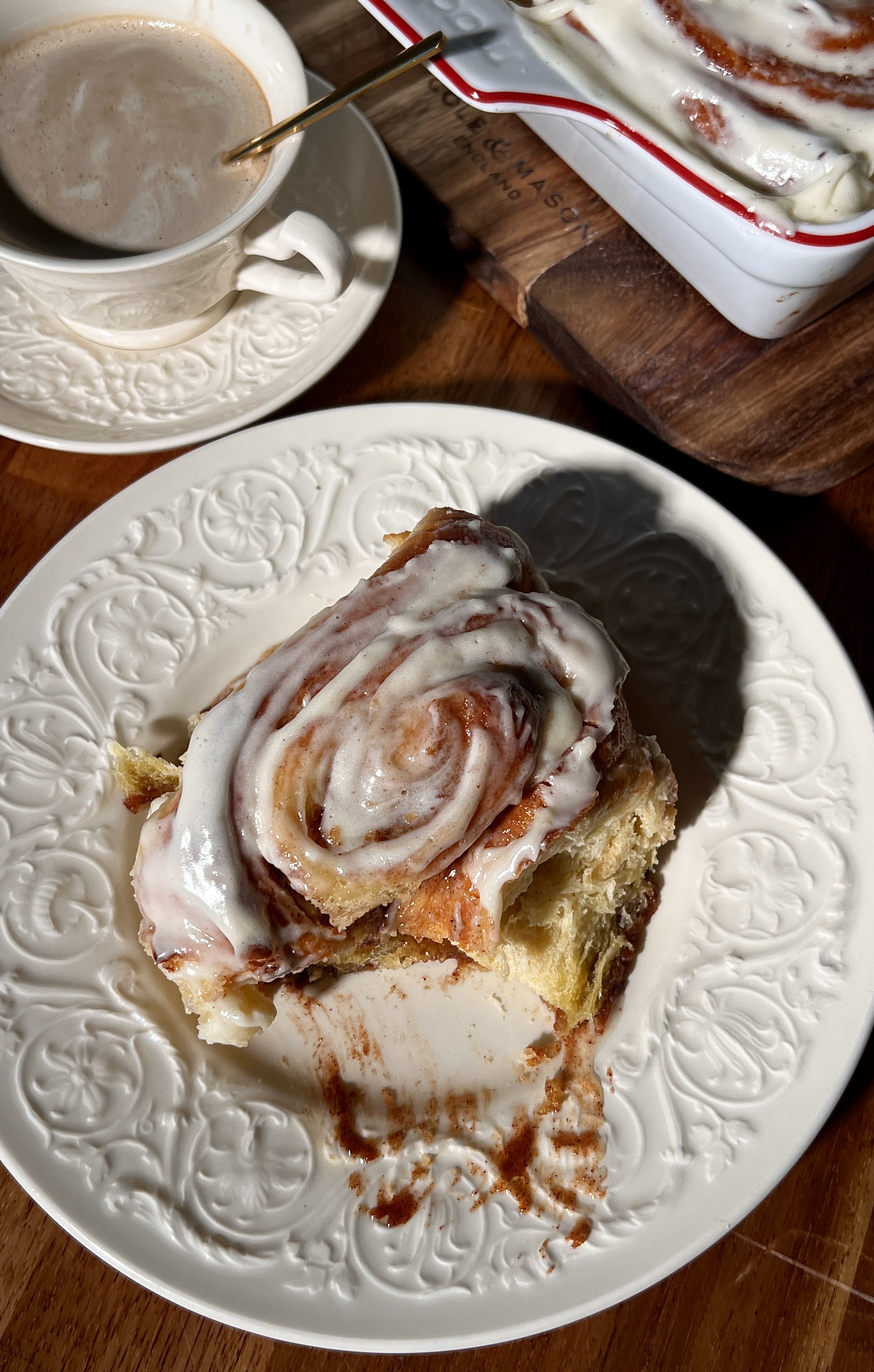 Soft, gooey eggnog cinnamon rolls in a baking dish, swirled with a golden brown sugar cinnamon filling and topped with melting eggnog cream cheese frosting.