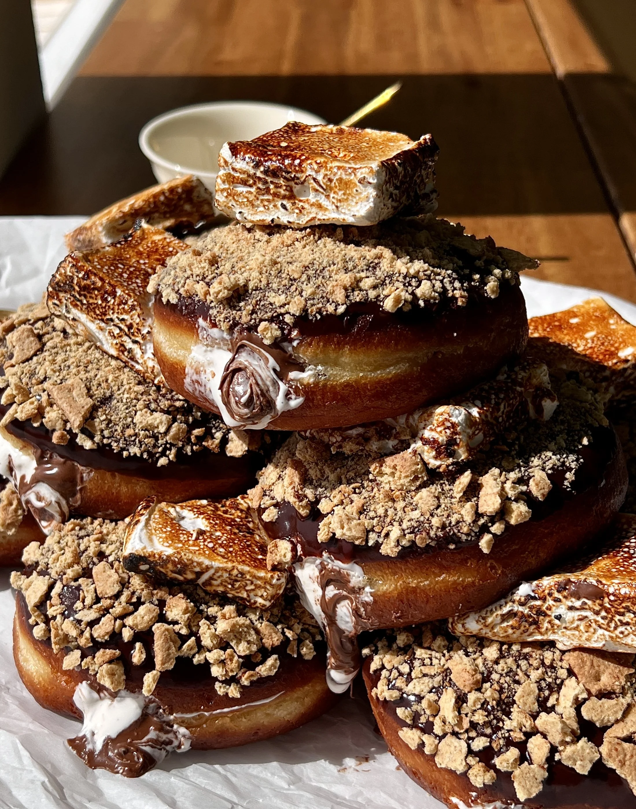 S'mores donuts filled with marshmallow buttercream and Nutella finished with chocolate ganache, crushed graham crackers, and a toasted marshmallow on top.