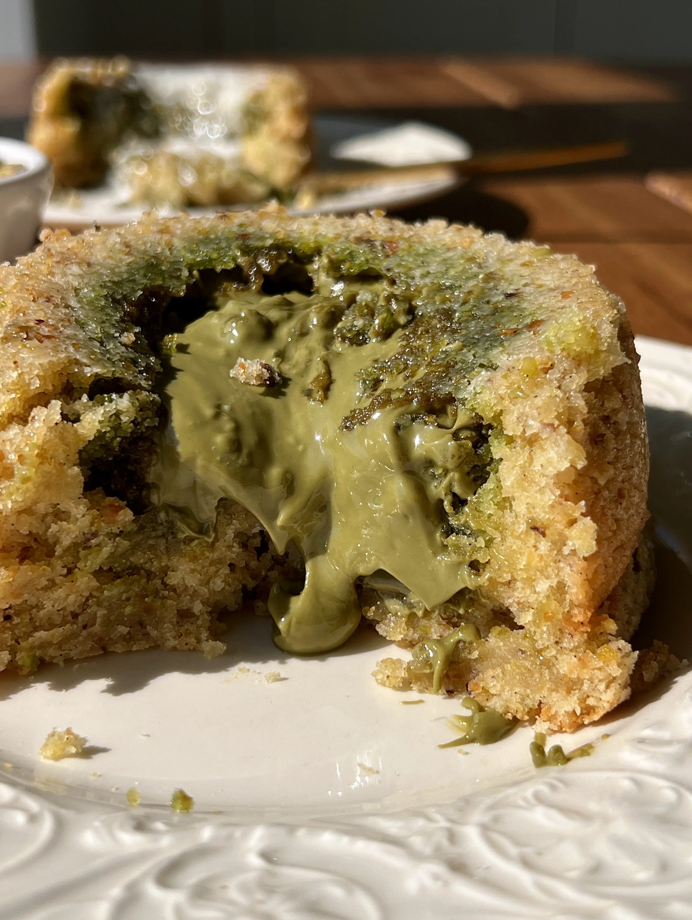 Close-up of a warm pistachio cream lava cake with a soft and tender pistachio cake exterior and a gooey molten pistachio cream center flowing out.