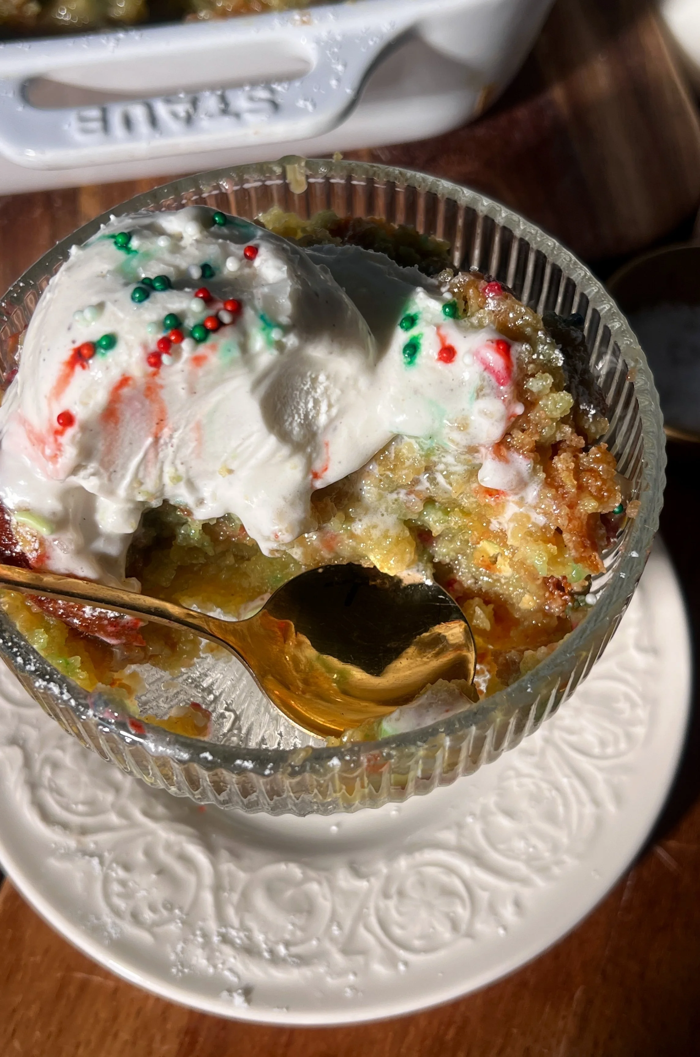 Warm slice of sugar cookie gooey butter cake with a soft sugar cookie base, a gooey cream cheese topping, a crackly golden surface, and a scoop of vanilla ice cream melting beside it.