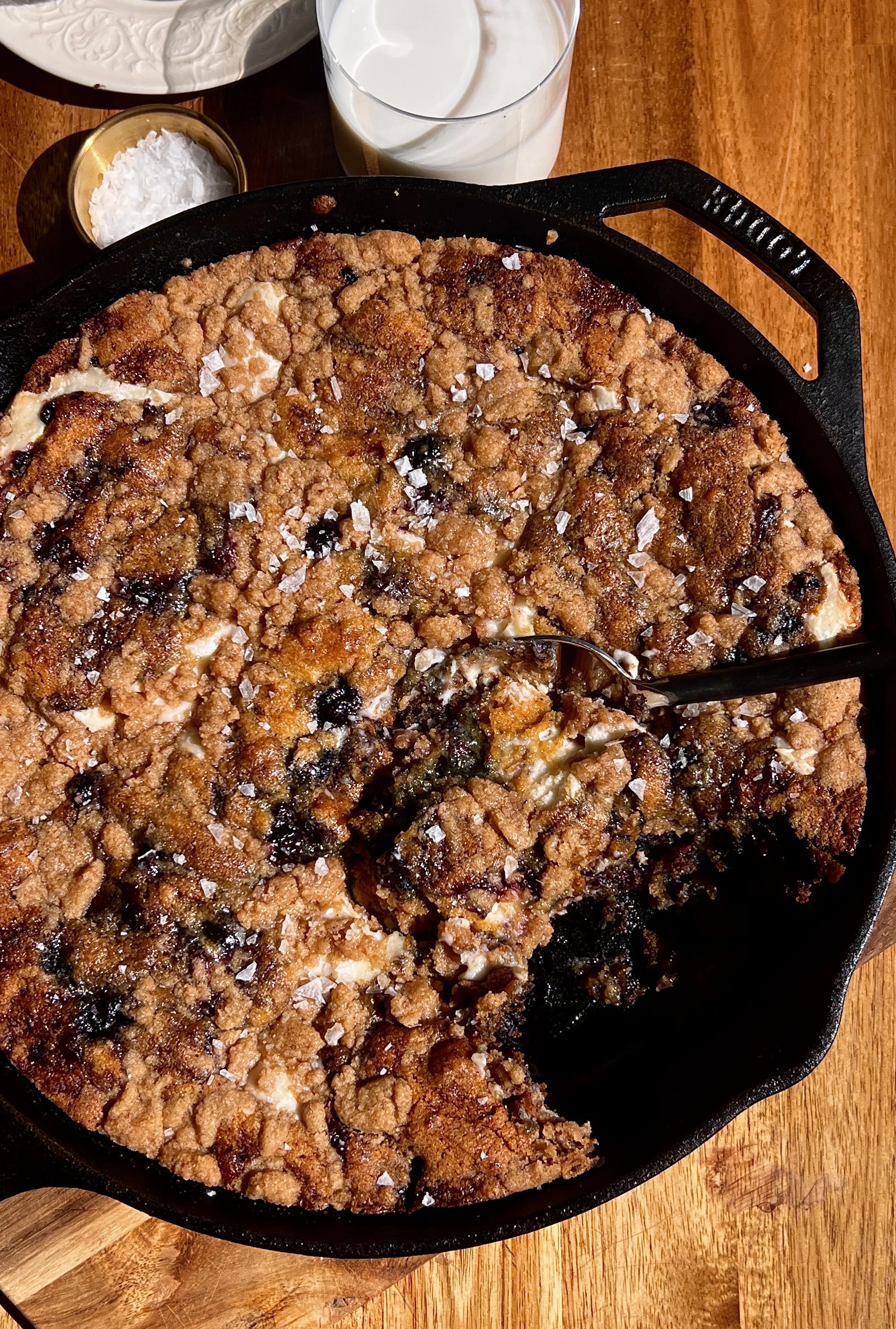 Brown butter cheesecake stuffed blueberry crumble cookie skillet served warm with vanilla ice cream and flaky sea salt.