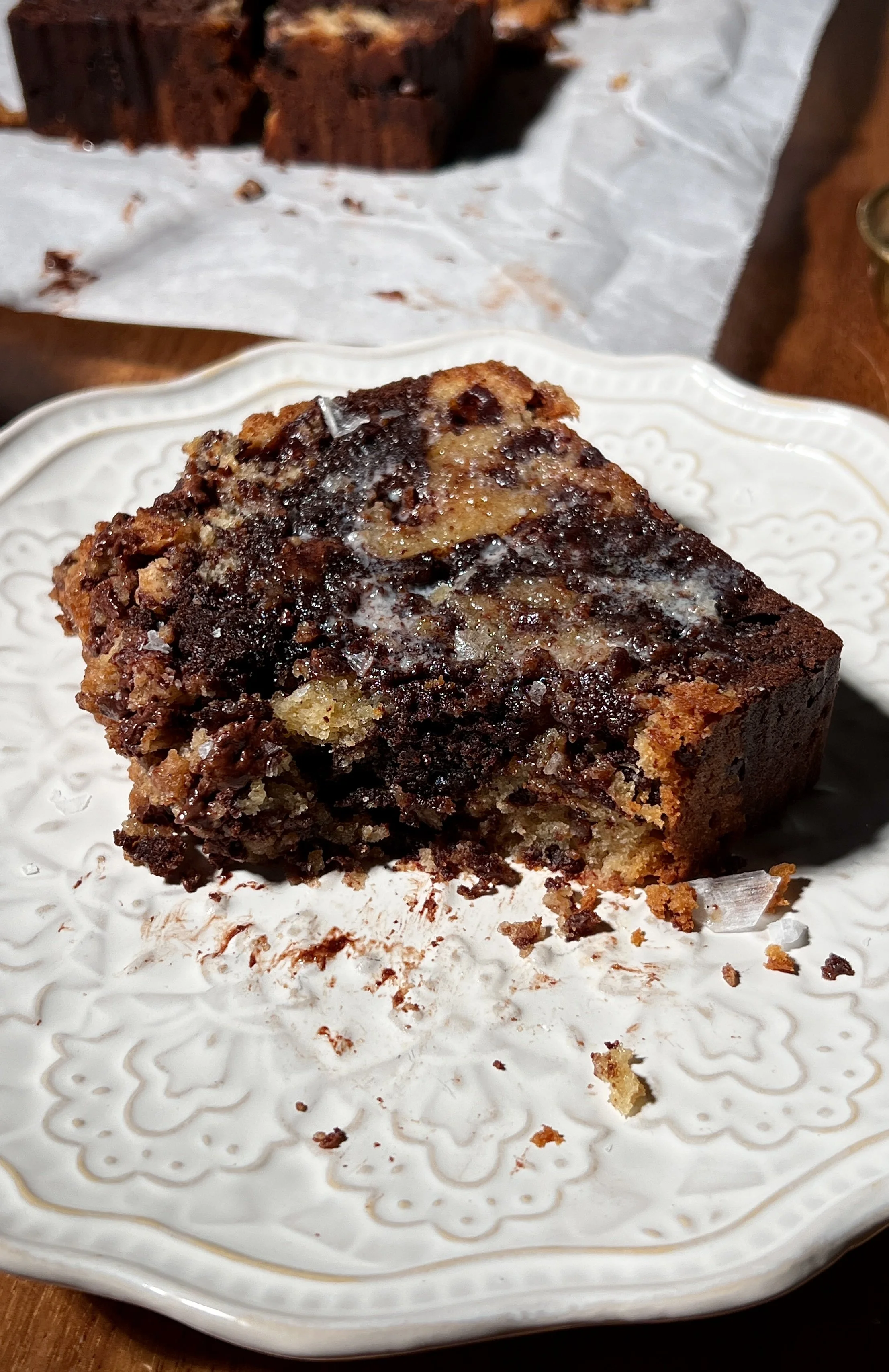 Brown butter marbled chocolate chip crumb loaf cake sliced and served warm, showing vanilla and chocolate swirled crumb, melty chocolate chips, and a buttery crumb topping, finished with flaky sea salt and coffee on the side.