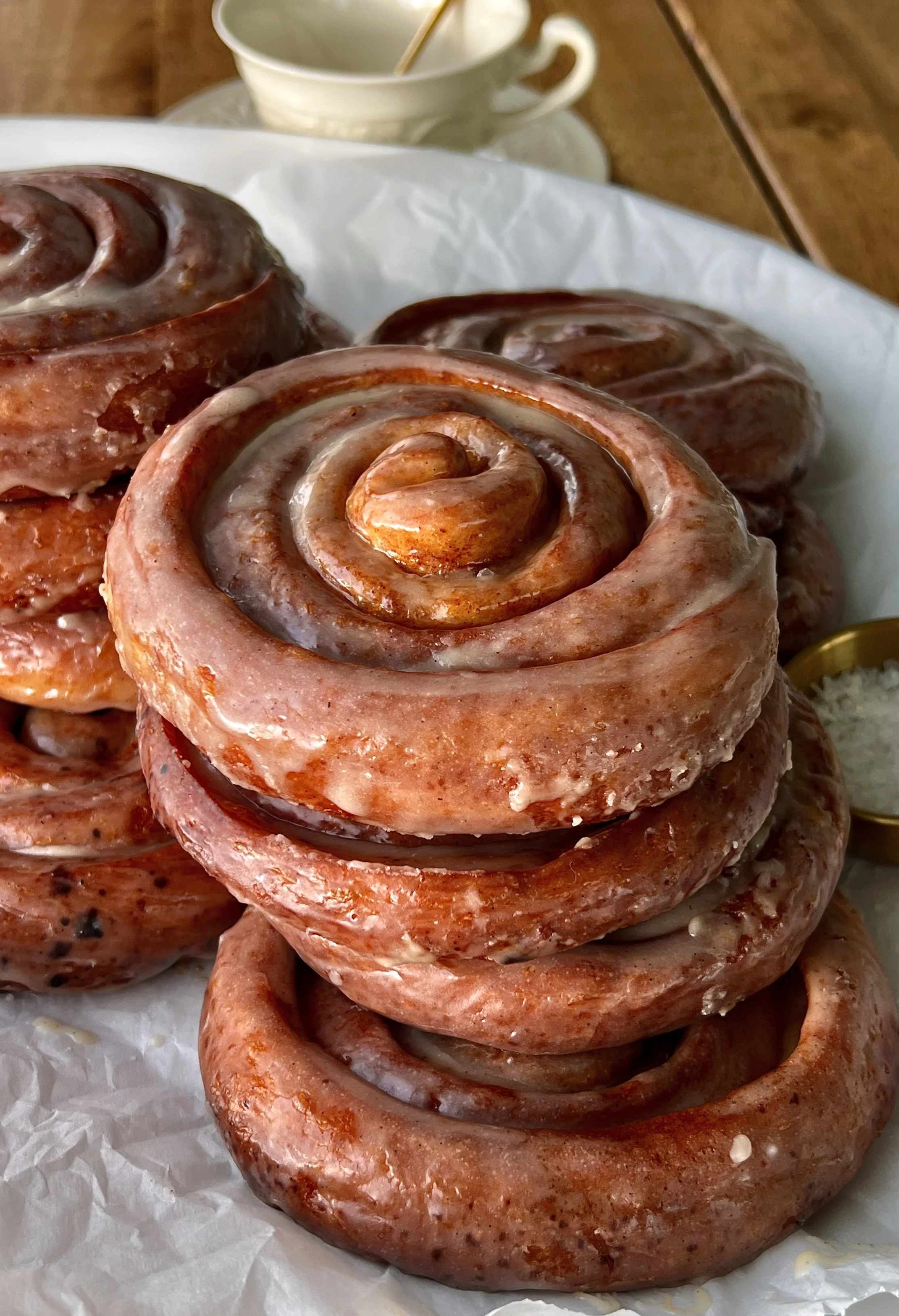 Pumpkin spice honey buns with a golden exterior coated in a honey glaze served warm with a hot cup of coffee.