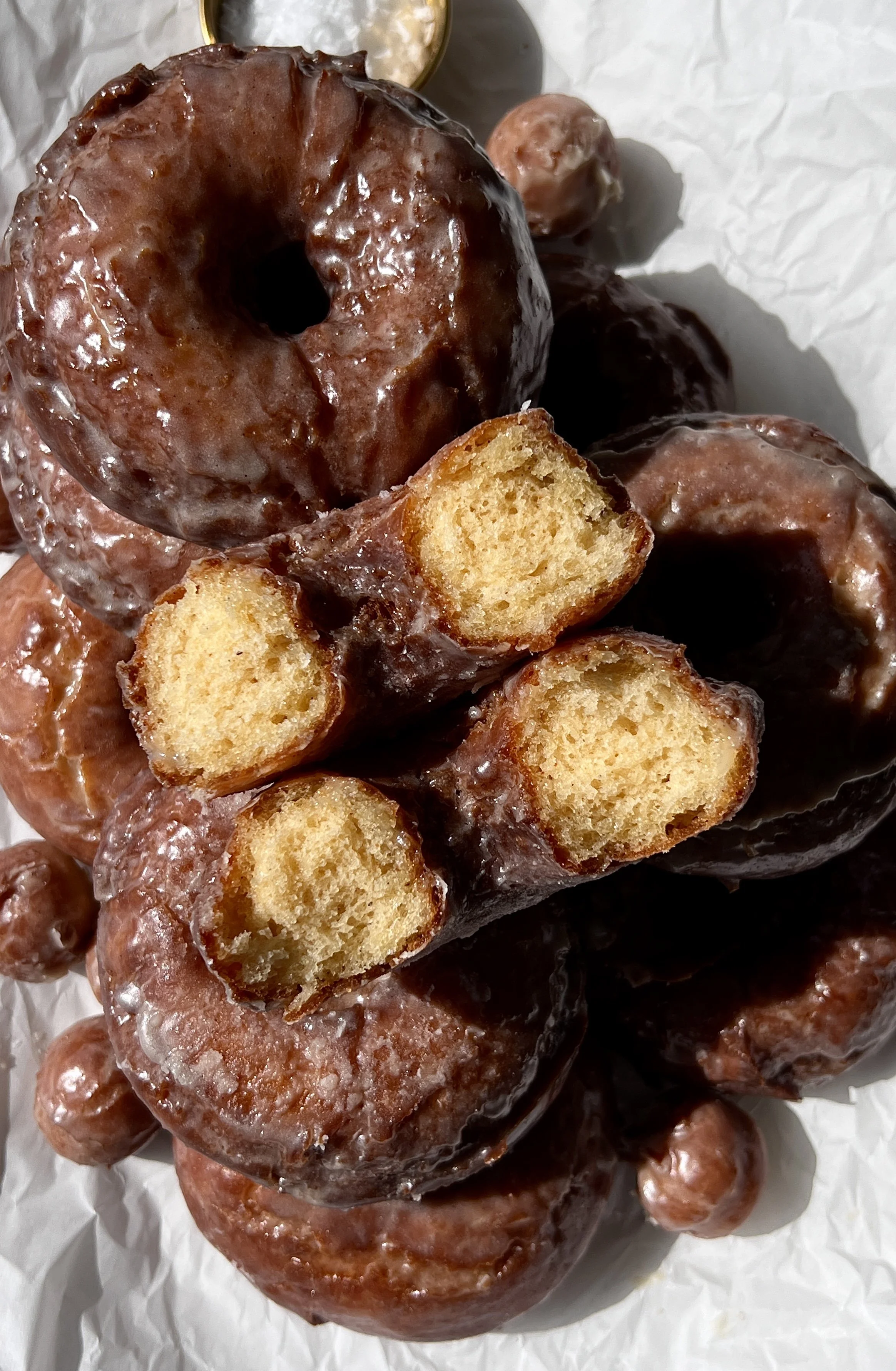 Close-up of a soft and fluffy old-fashioned sour cream donut with a beautifully golden and slightly crisp exterior coated in a silky vanilla bean glaze.