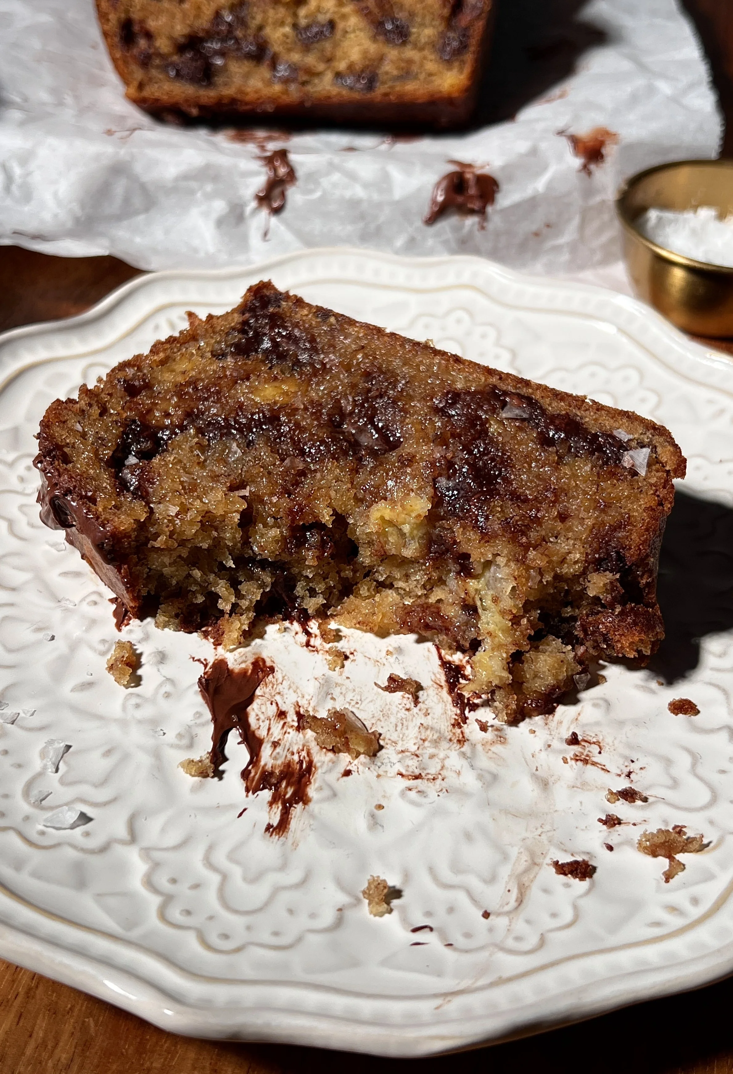 Brown butter banana bread loaf with melty chocolate chips, baked until golden, sliced and served warm with butter, flaky sea salt, and a cup of coffee.