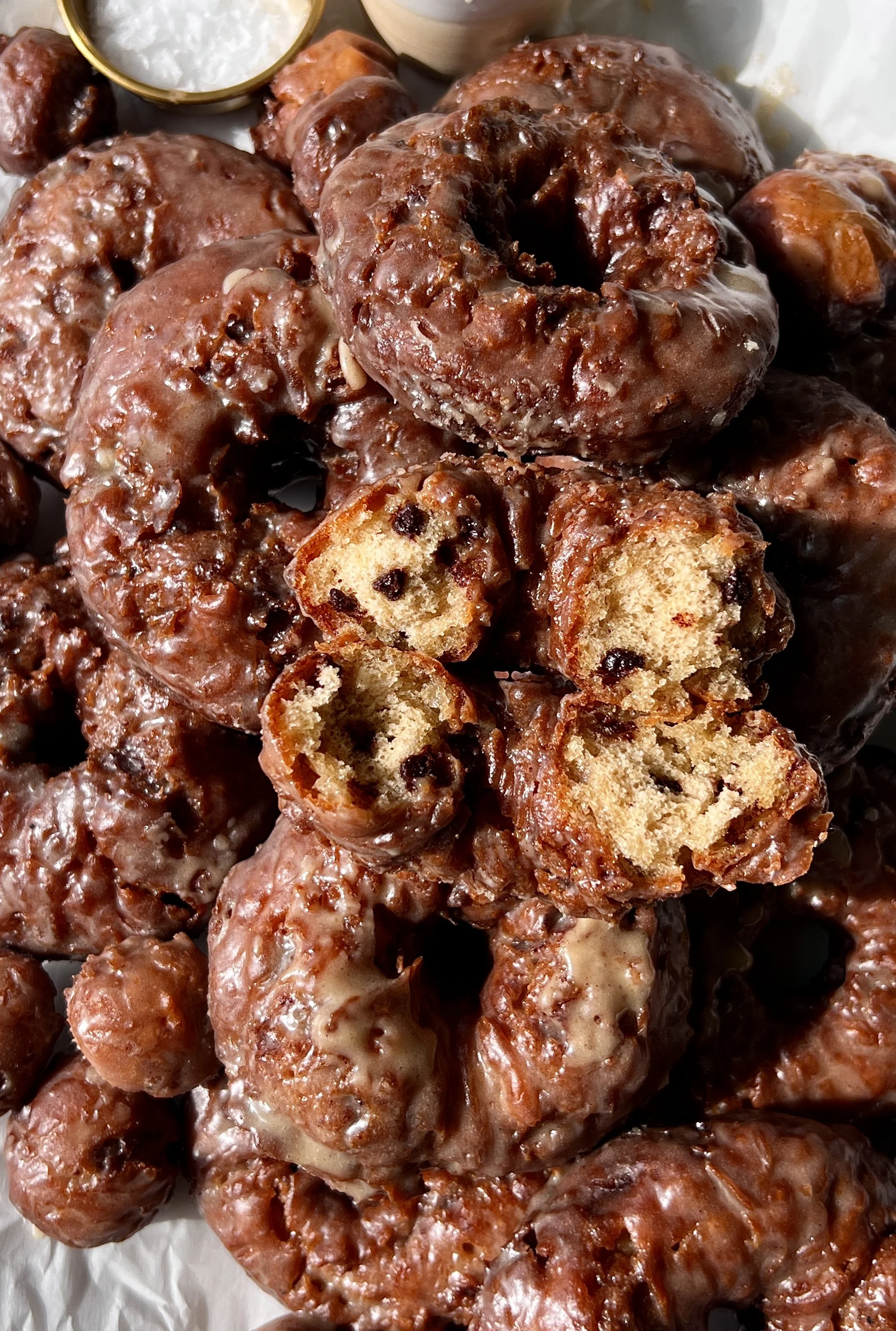 Close-up of a fluffy old-fashioned chocolate chip banana bread donut with a golden crisp exterior coated in a silky salted brown butter honey glaze.