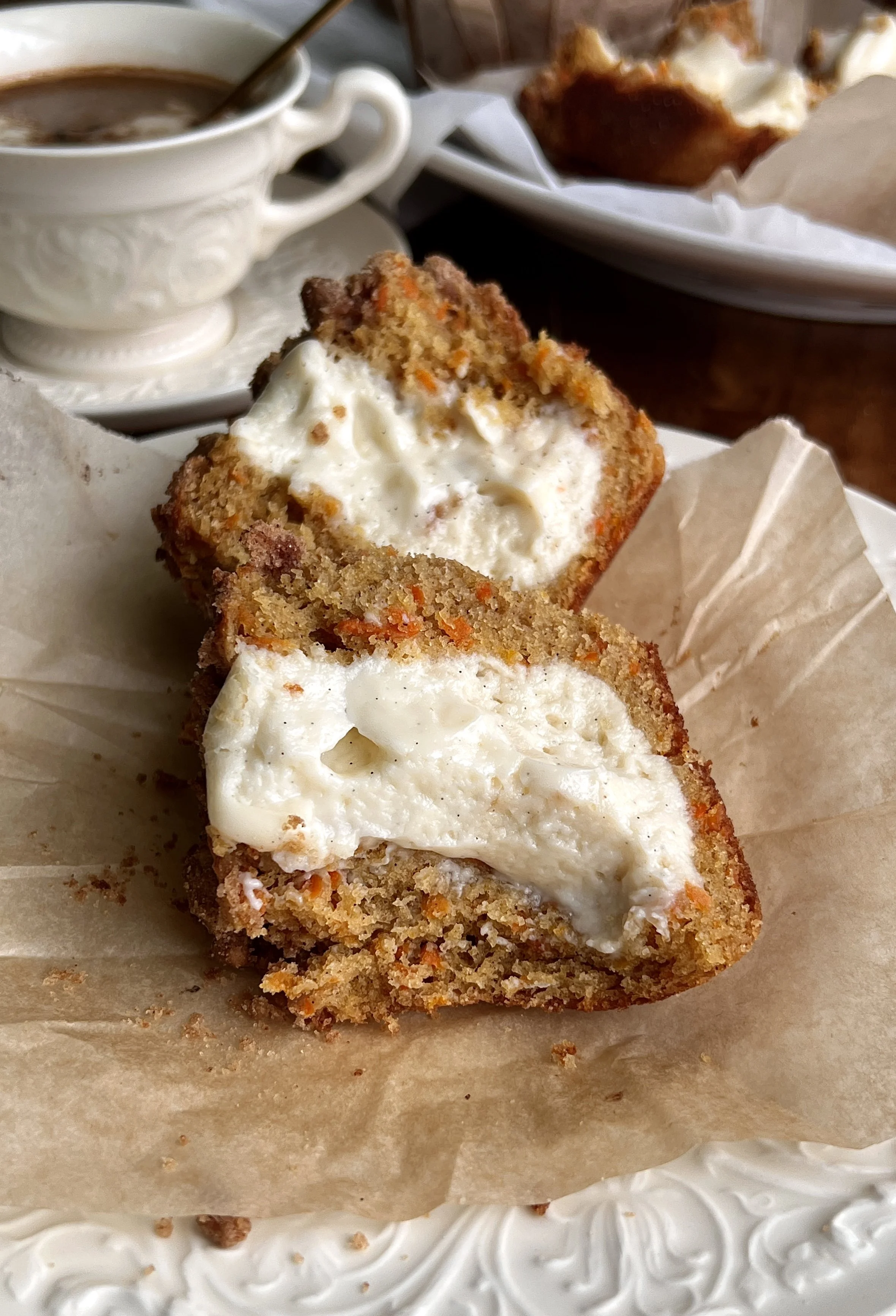 Warm carrot cake cream cheese muffins with pecan streusel served with a hot cup of coffee.