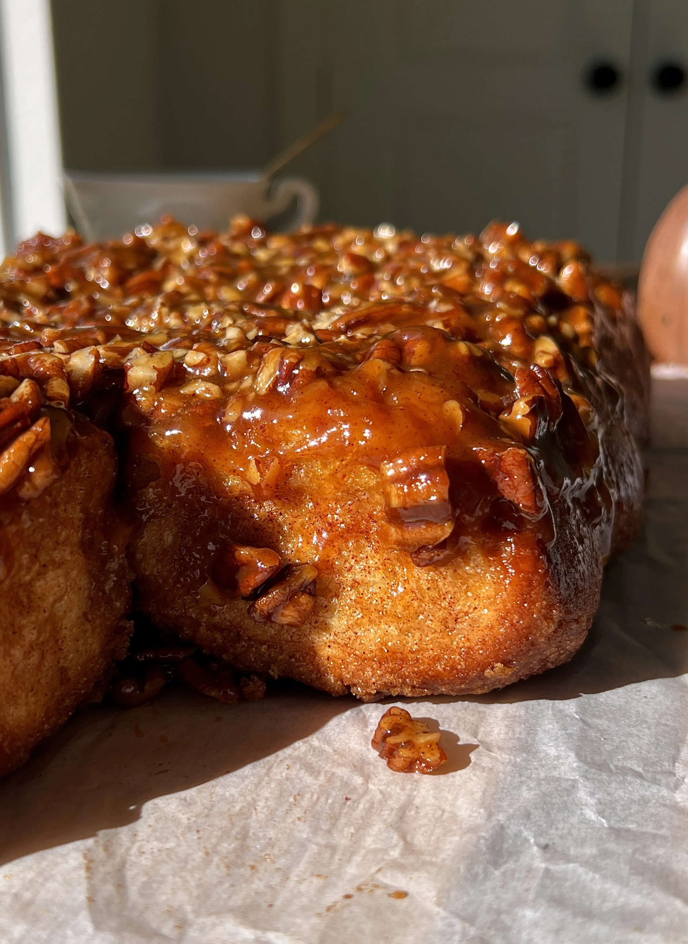 Option 1 (Primary / Hero Image) Sweet potato sticky rolls with a gooey caramelized sticky pecan topping served warm with a steaming hot cup of coffee.