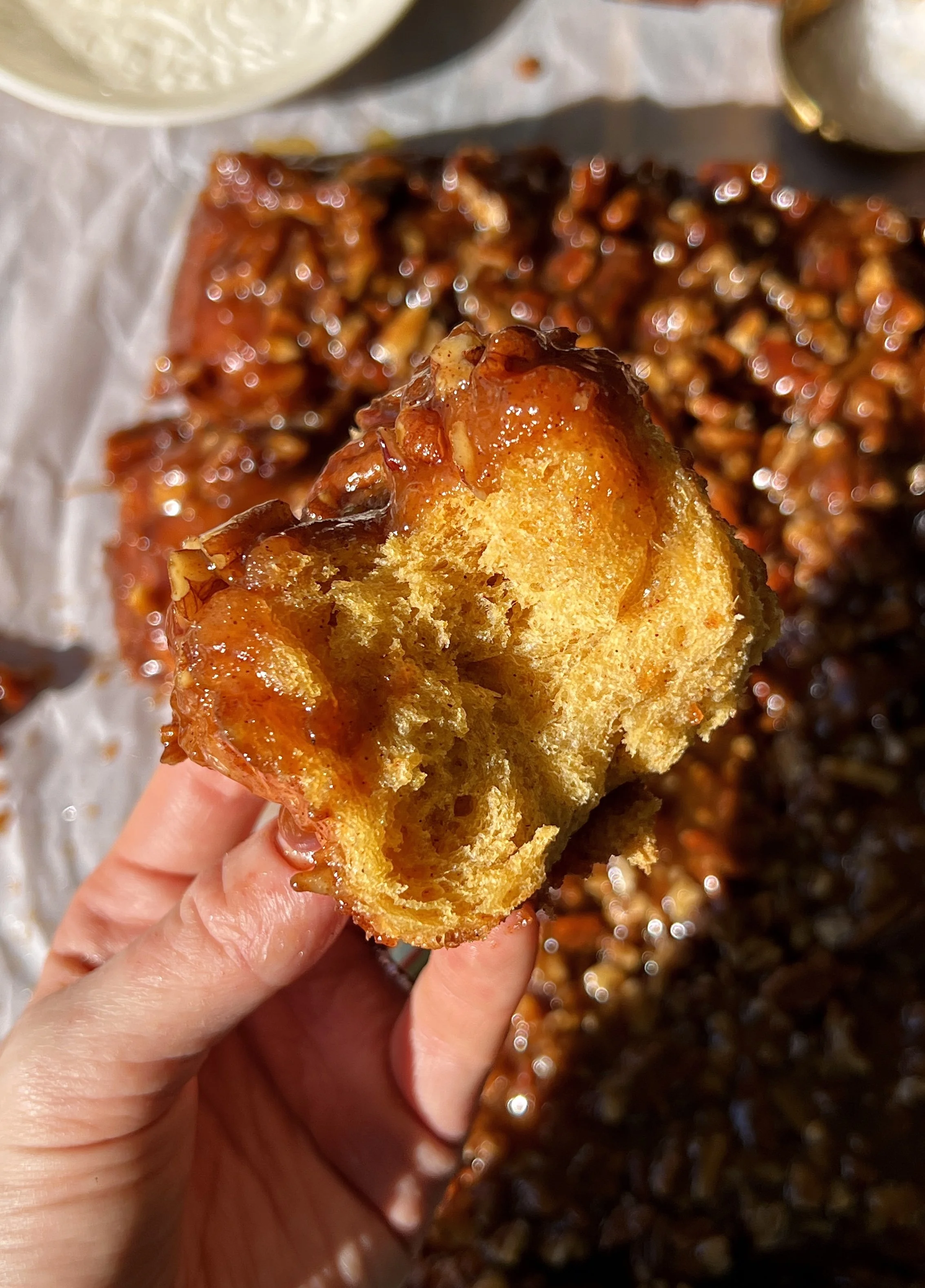 Close-up of a sweet potato sticky roll showing the pillowy soft fluffy and tender spiced sweet potato interior with a gooey caramelized sticky pecan topping.