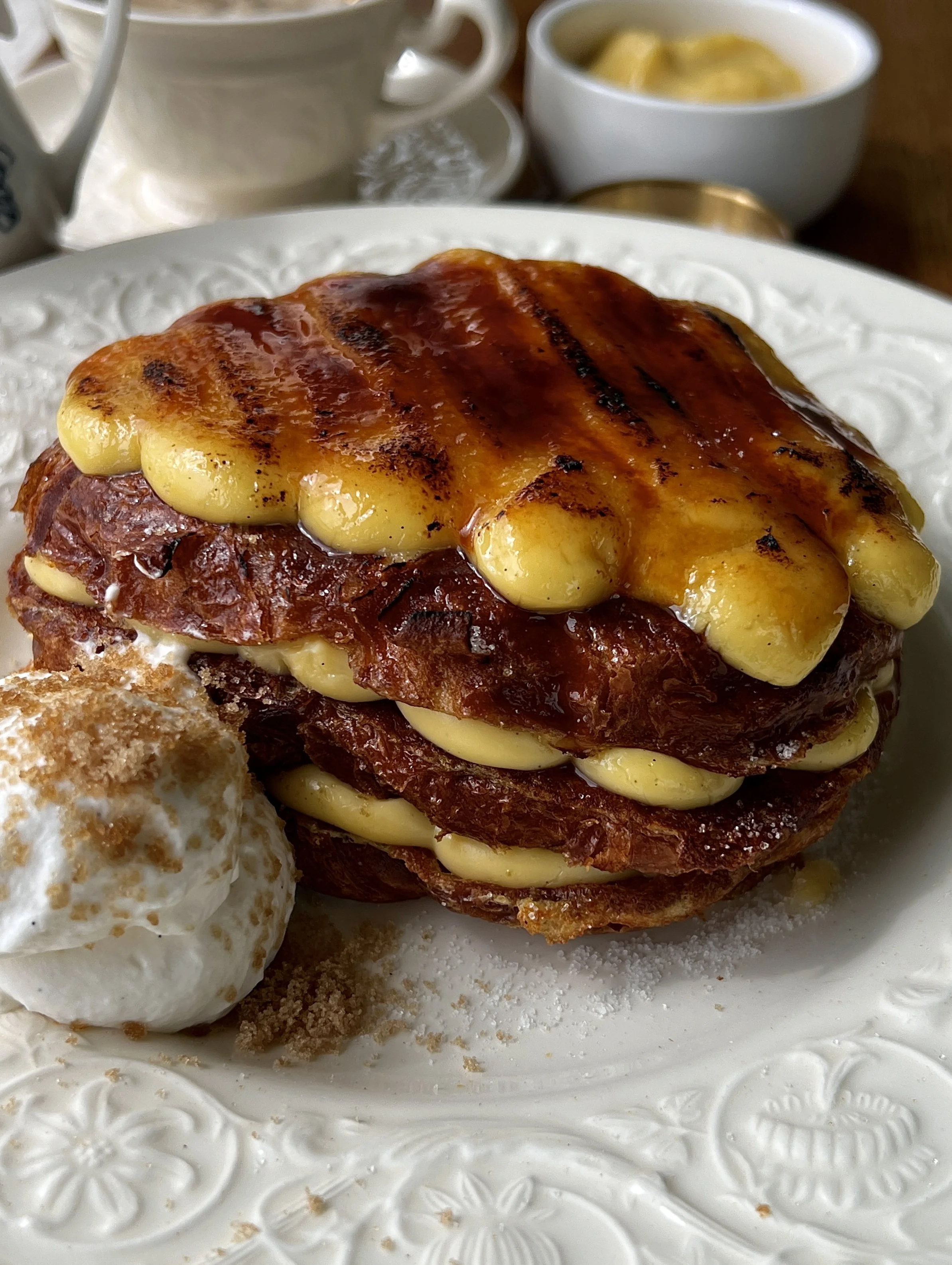 Close-up of crème brûlée croissant french toast showing the perfectly golden pan-fried croissant with a thick creamy vanilla bean custard and crisp caramelized sugar layer on top.