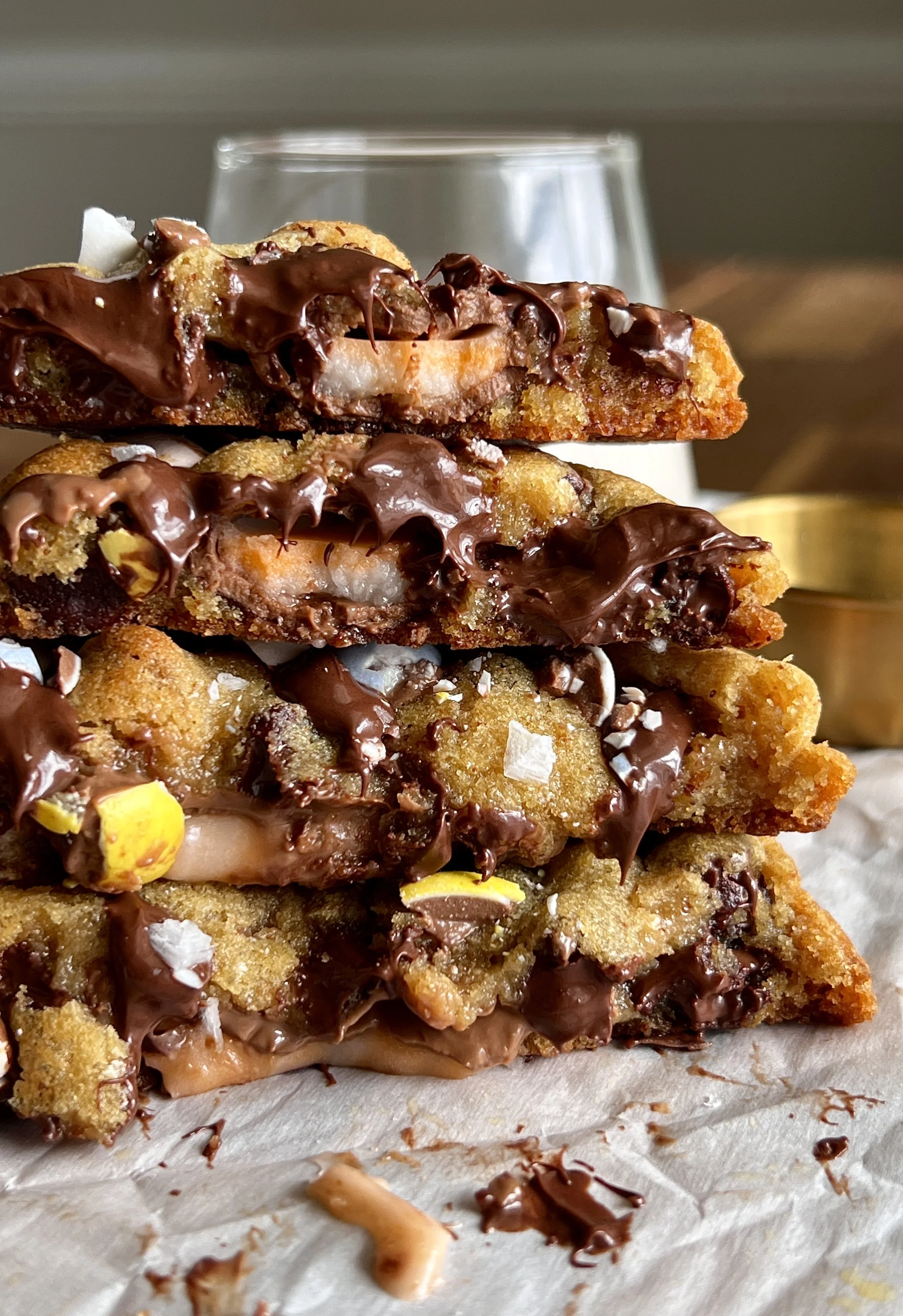 Brown butter Cadbury Creme Egg chocolate chip cookies with gooey centers, crisp edges, melty chocolate chips, crushed mini eggs, and a Creme Egg center, served with flaky sea salt and milk.