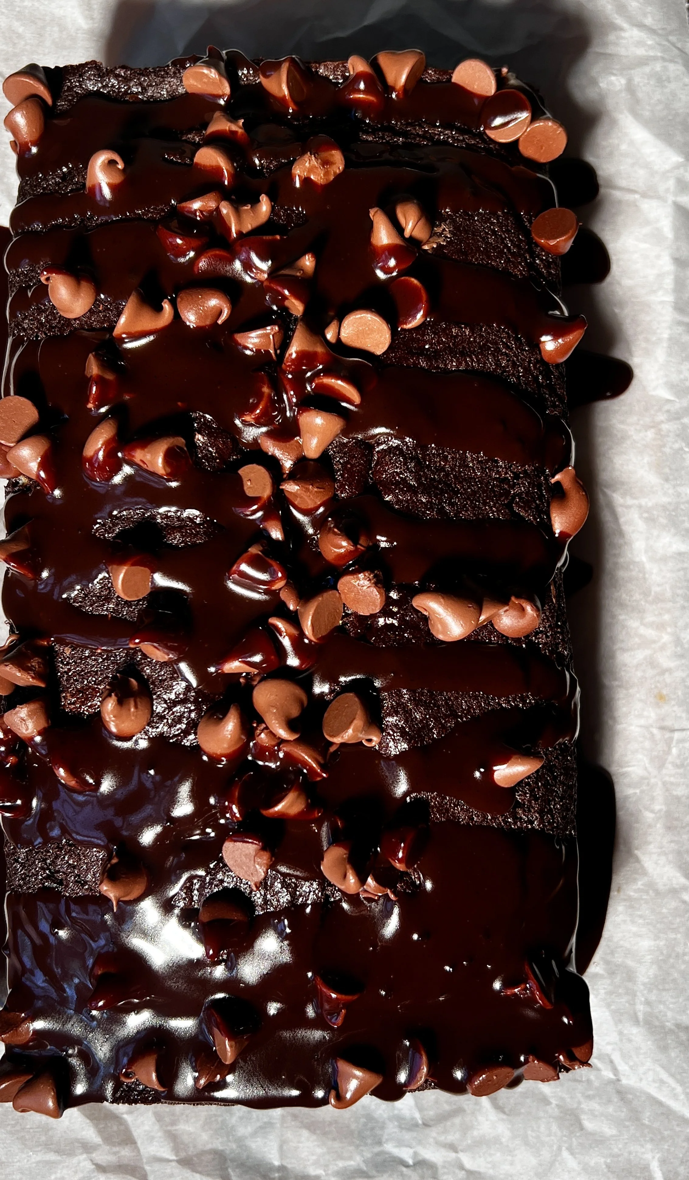 A warm and fudgy brown butter hot fudge brownie loaf with crisp edges, a gooey chocolate center, melty hot fudge sauce, vanilla ice cream, and flaky sea salt on top.