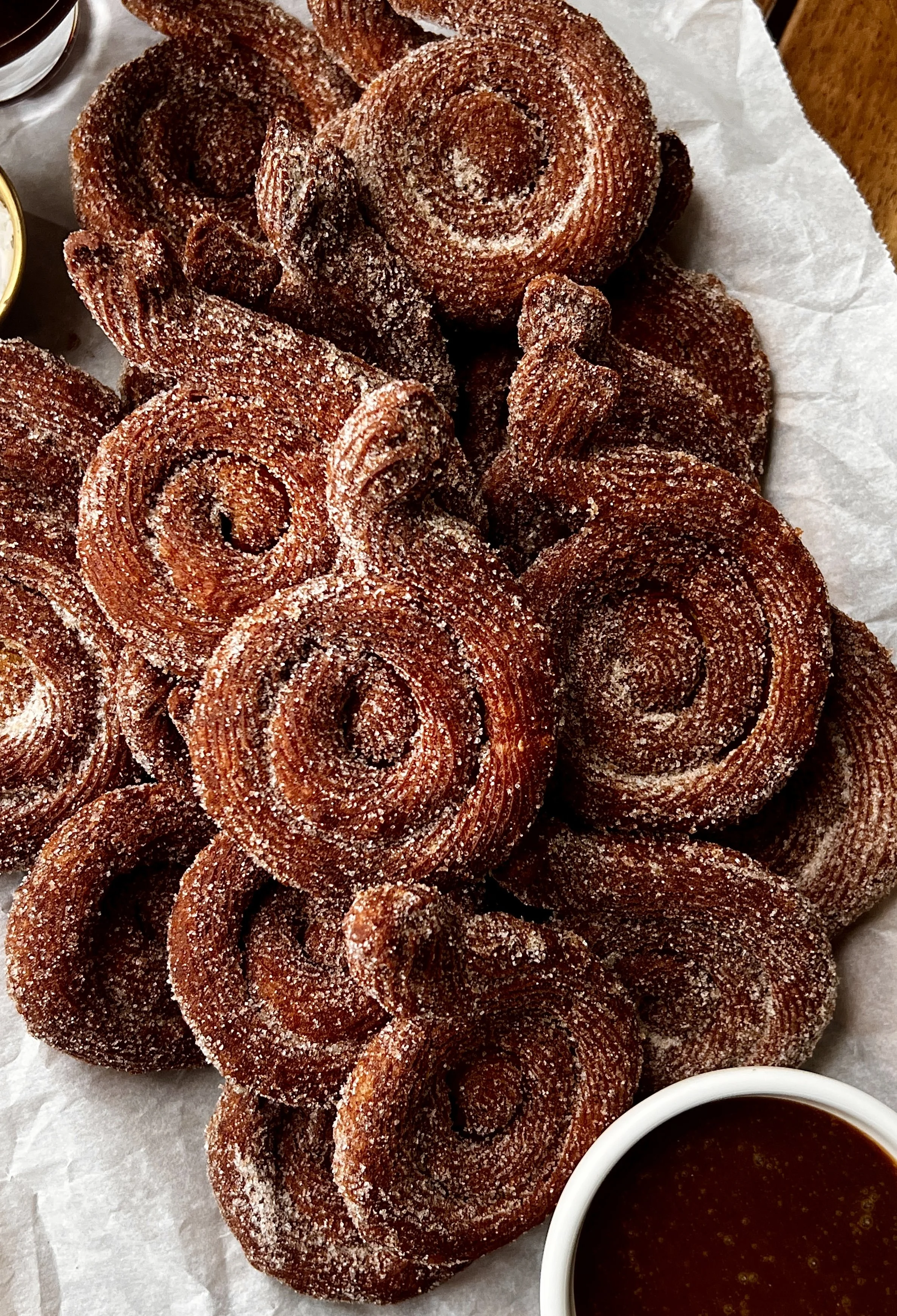 Close-up of pumpkin-shaped Brown Butter Pumpkin Churros coated in cinnamon sugar and served with salted chocolate and caramel sauce