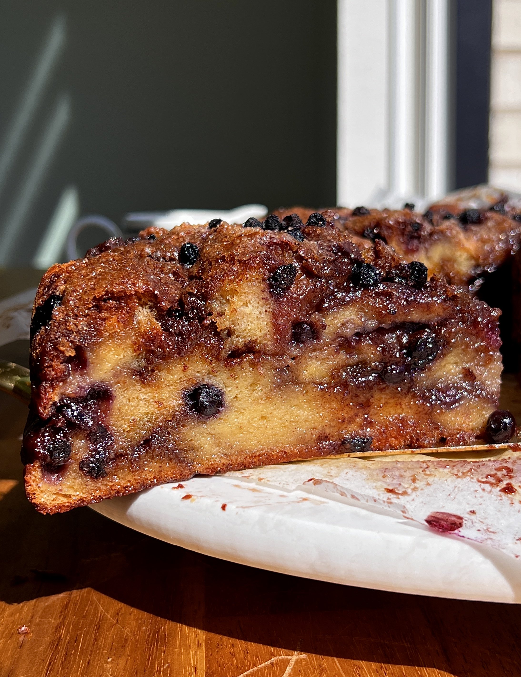 Close-up of blueberry cinnamon roll bread pudding with bright blueberries and a gooey brown sugar cinnamon swirl throughout.