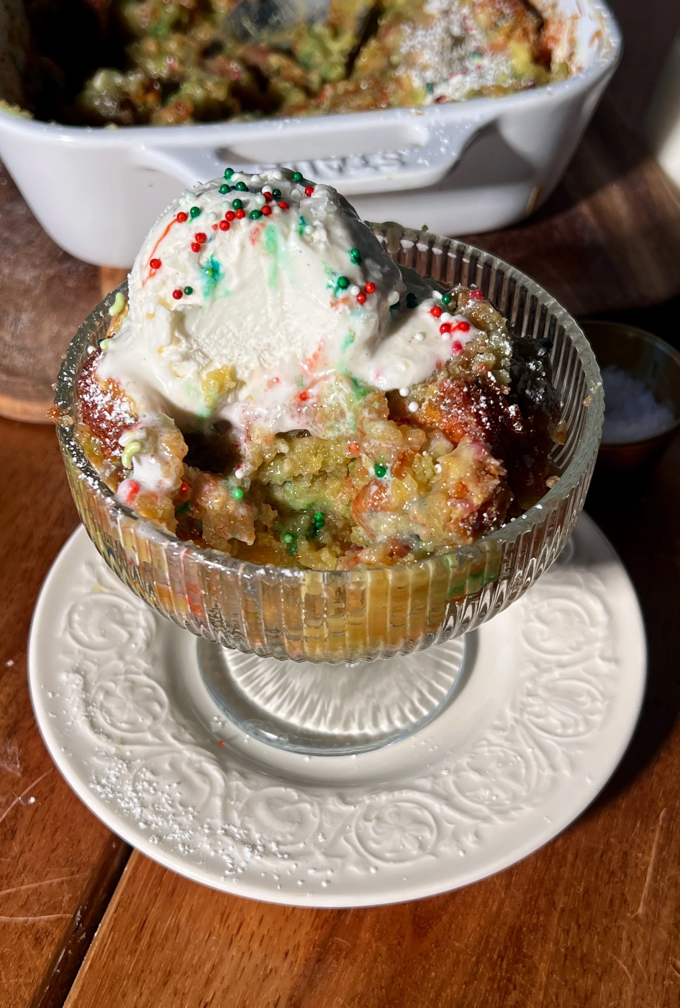 Warm slice of sugar cookie gooey butter cake with a soft sugar cookie base, a gooey cream cheese topping, a crackly golden surface, and a scoop of vanilla ice cream melting beside it.