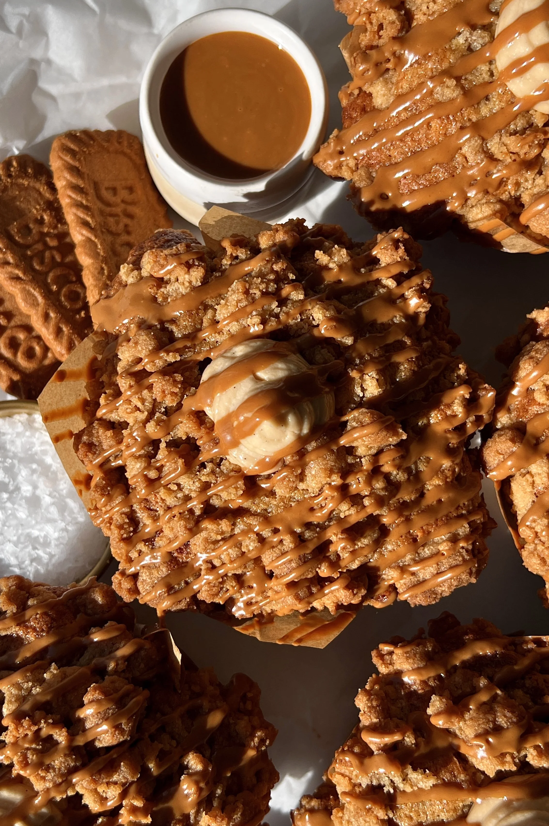 Close-up of a bakery-style banana Biscoff muffin showing the soft fluffy tender banana crumb with a rich Biscoff cream cheese filling and Biscoff cookie butter inside and a golden Biscoff streusel topping.