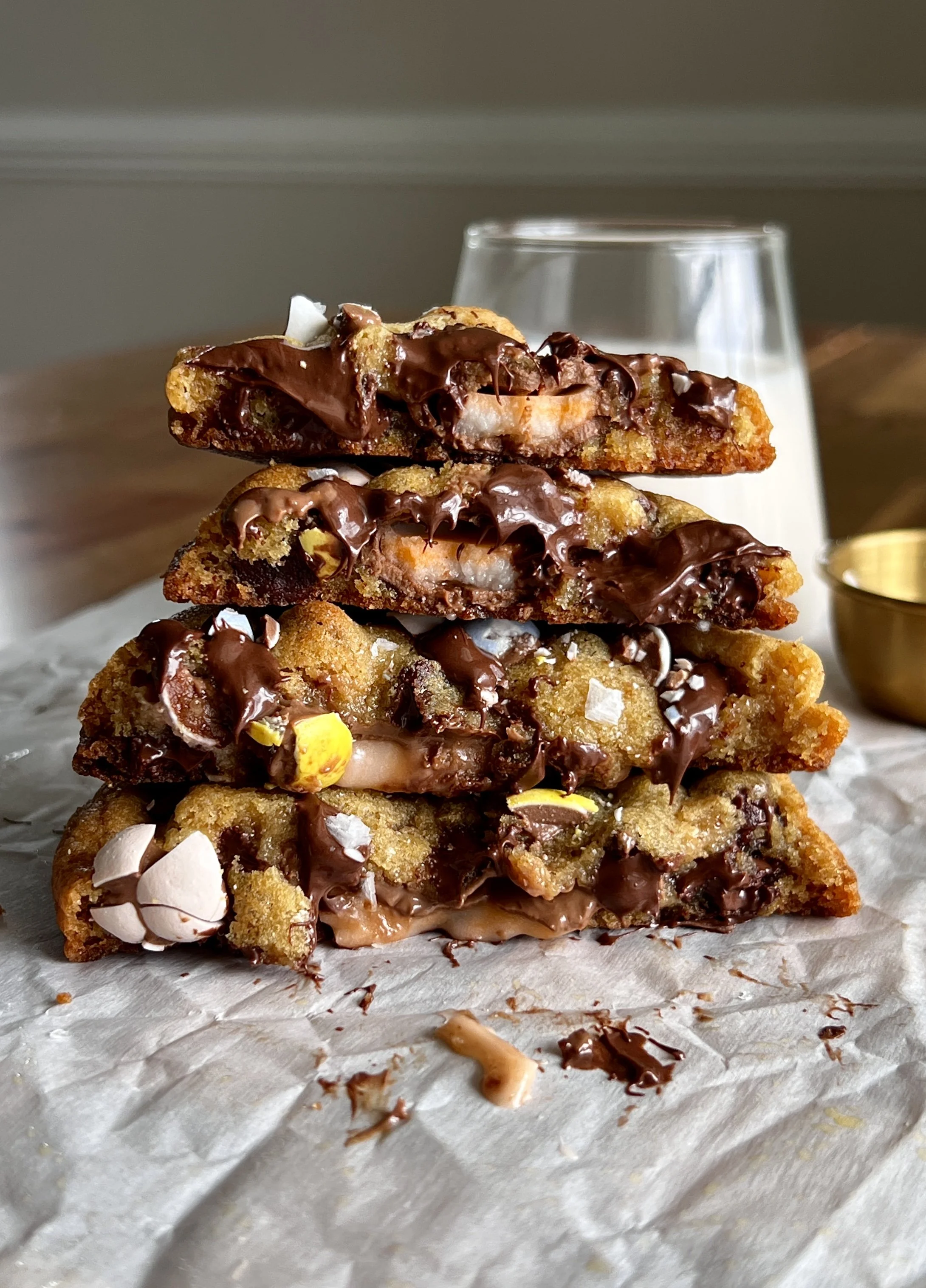 Brown butter Cadbury Creme Egg chocolate chip cookies with gooey centers, crisp edges, melty chocolate chips, crushed mini eggs, and a Creme Egg center, served with flaky sea salt and milk.