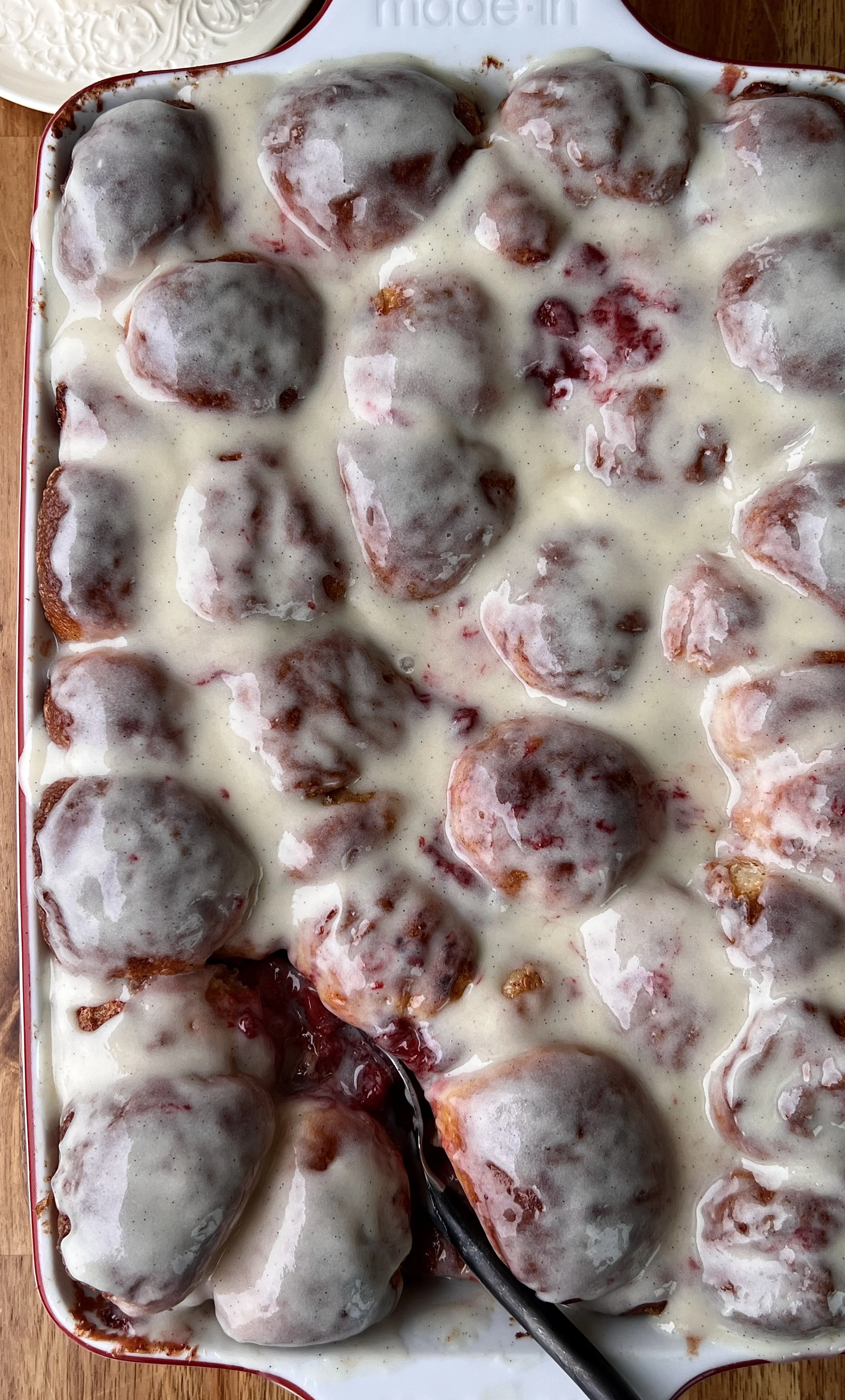 Close-up of soft and fluffy strawberry cinnamon roll bites rolled in brown sugar cinnamon with a glossy homemade strawberry compote and brown sugar syrup throughout.