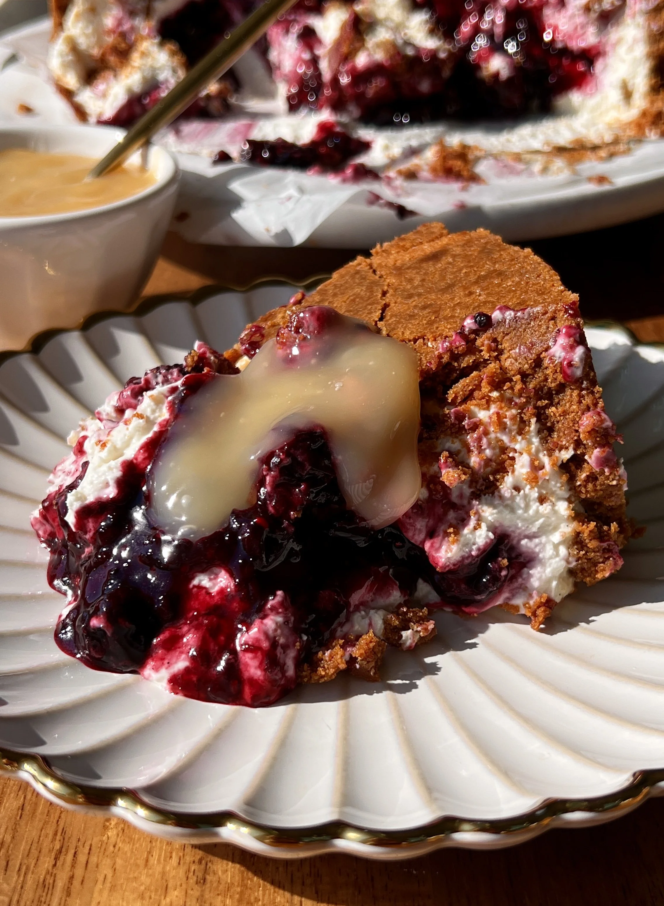 Upside down triple berry no-bake cheesecake with a perfectly crunchy Biscoff cookie crust inverted to serve and finished with a dollop of bright lemon curd on top.