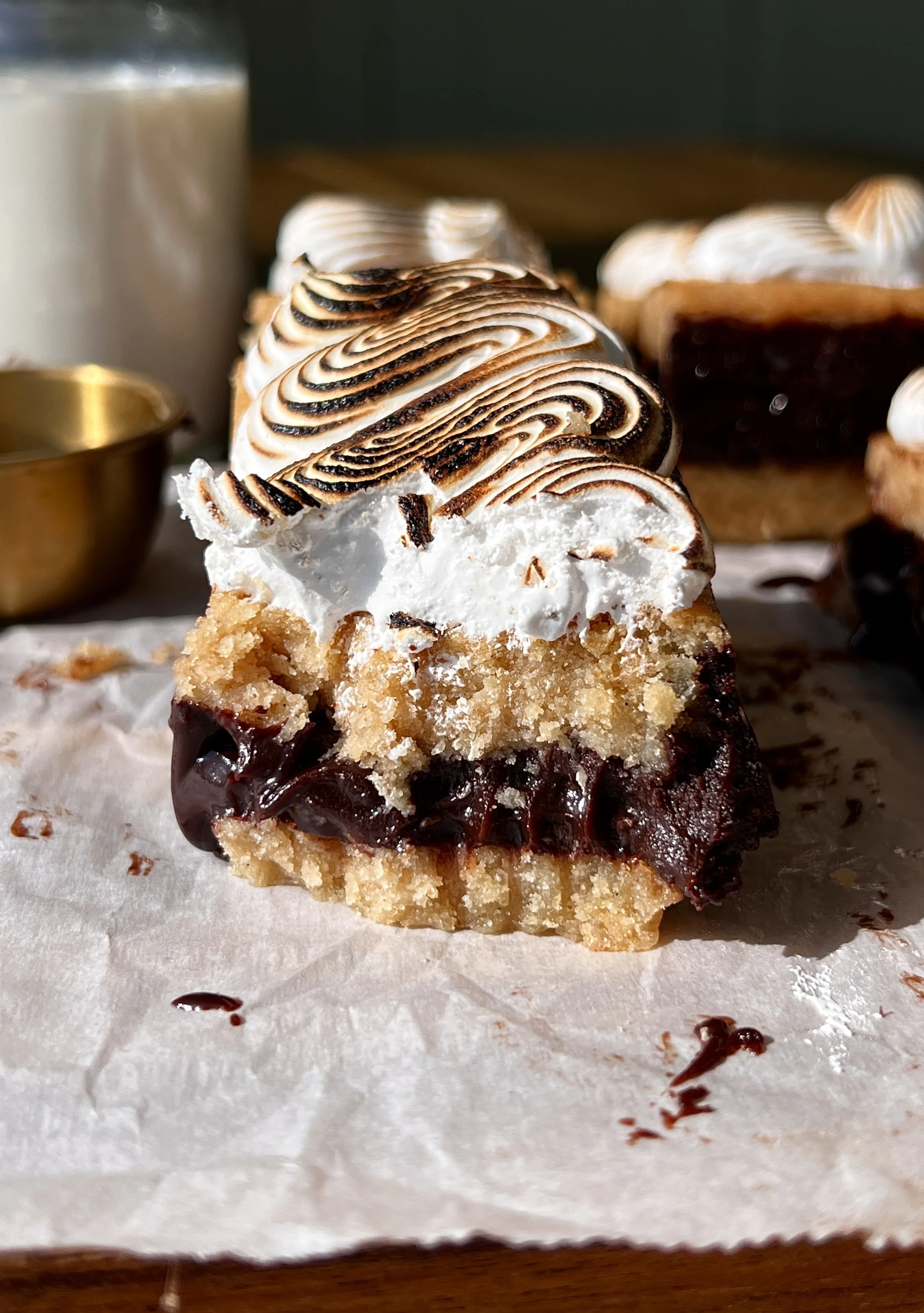 S'mores fudge shortbread bar with a bite taken out showing the soft buttery graham cracker shortbread base, rich fudge layer, and toasted marshmallow creme inside.