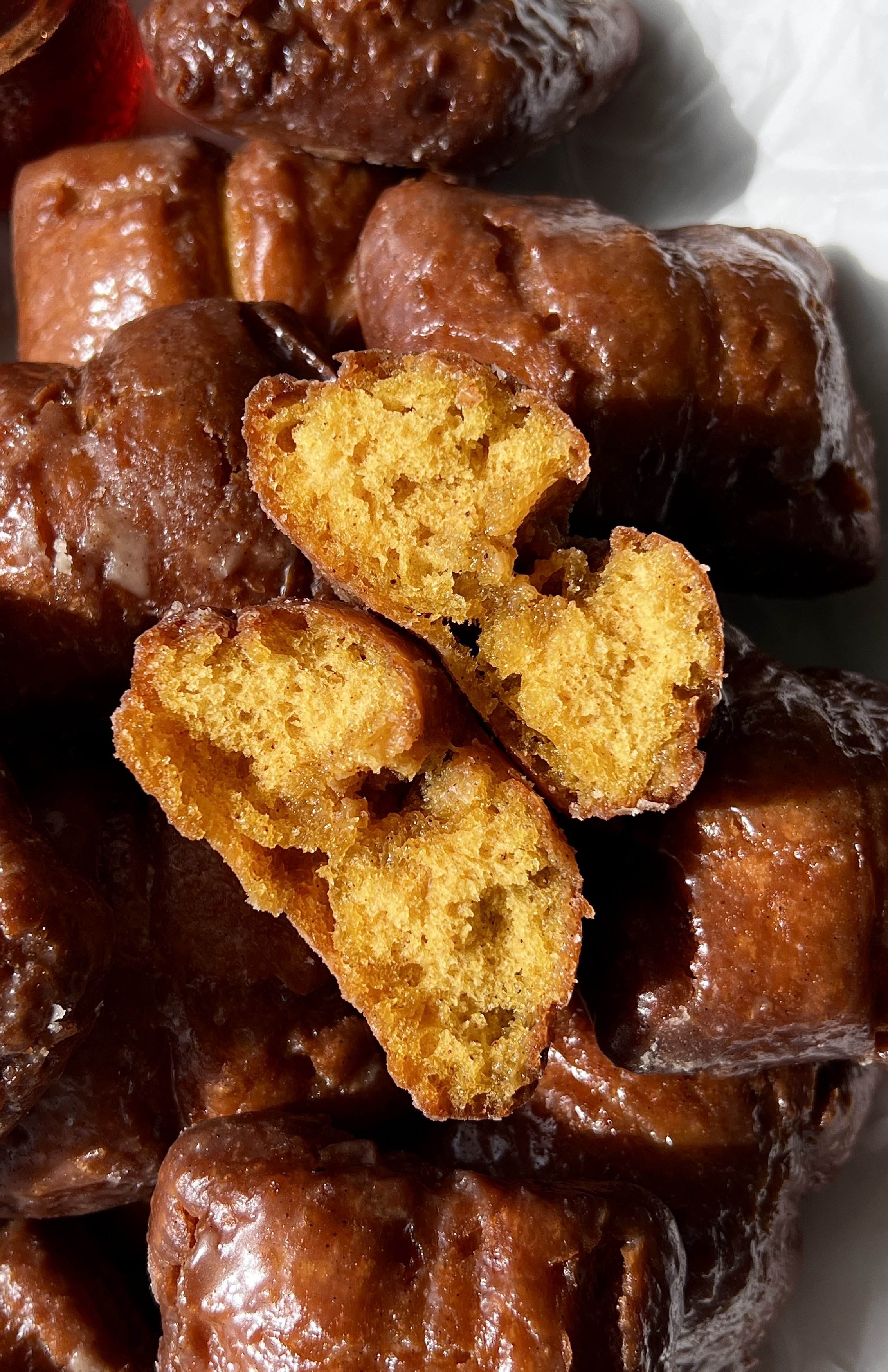 Close-up of an old-fashioned pumpkin donut bar showing the soft and fluffy delicate crumb with a beautifully golden and crisp exterior coated in a salted maple cinnamon glaze throughout.