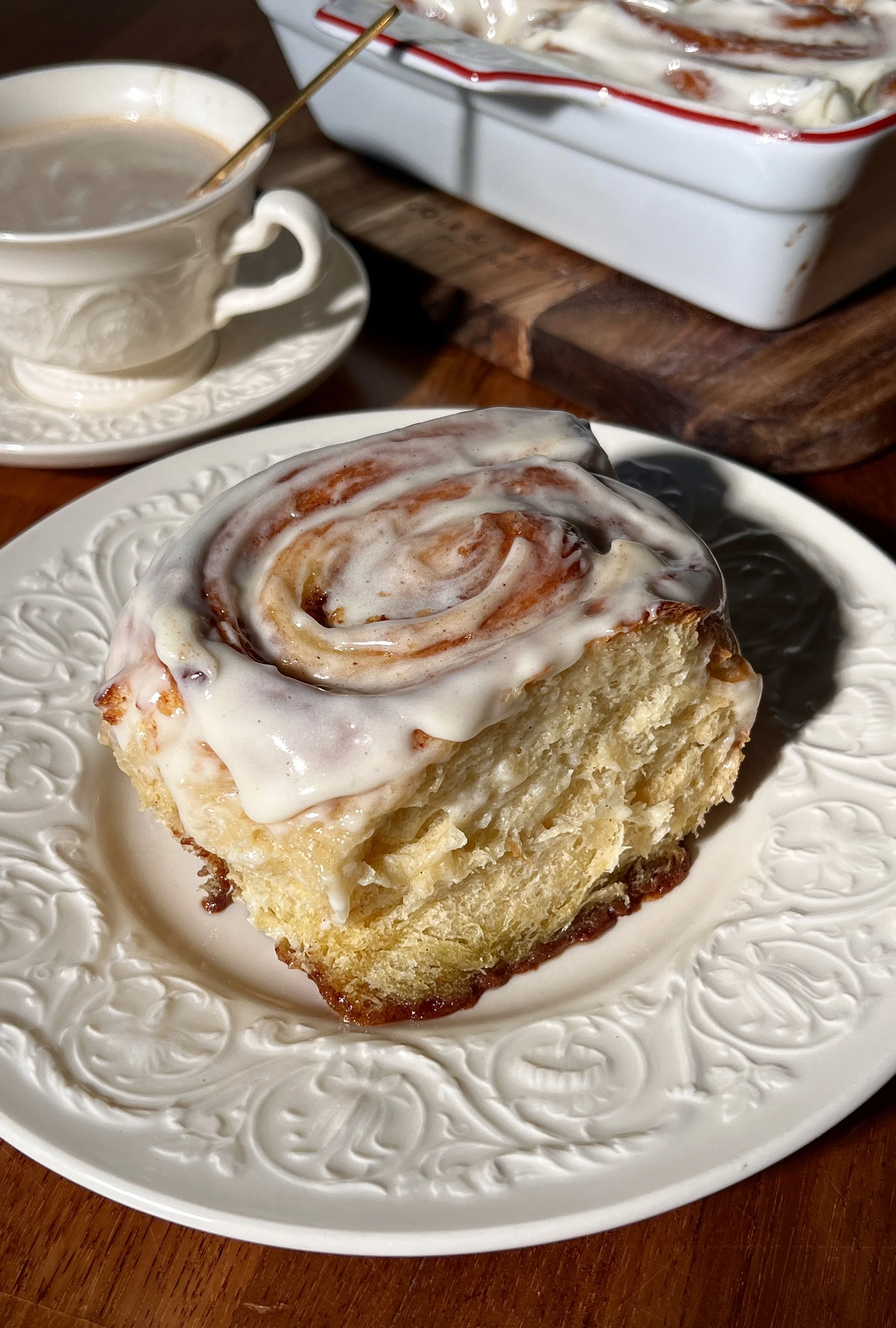 Soft, gooey eggnog cinnamon rolls in a baking dish, swirled with a golden brown sugar cinnamon filling and topped with melting eggnog cream cheese frosting.