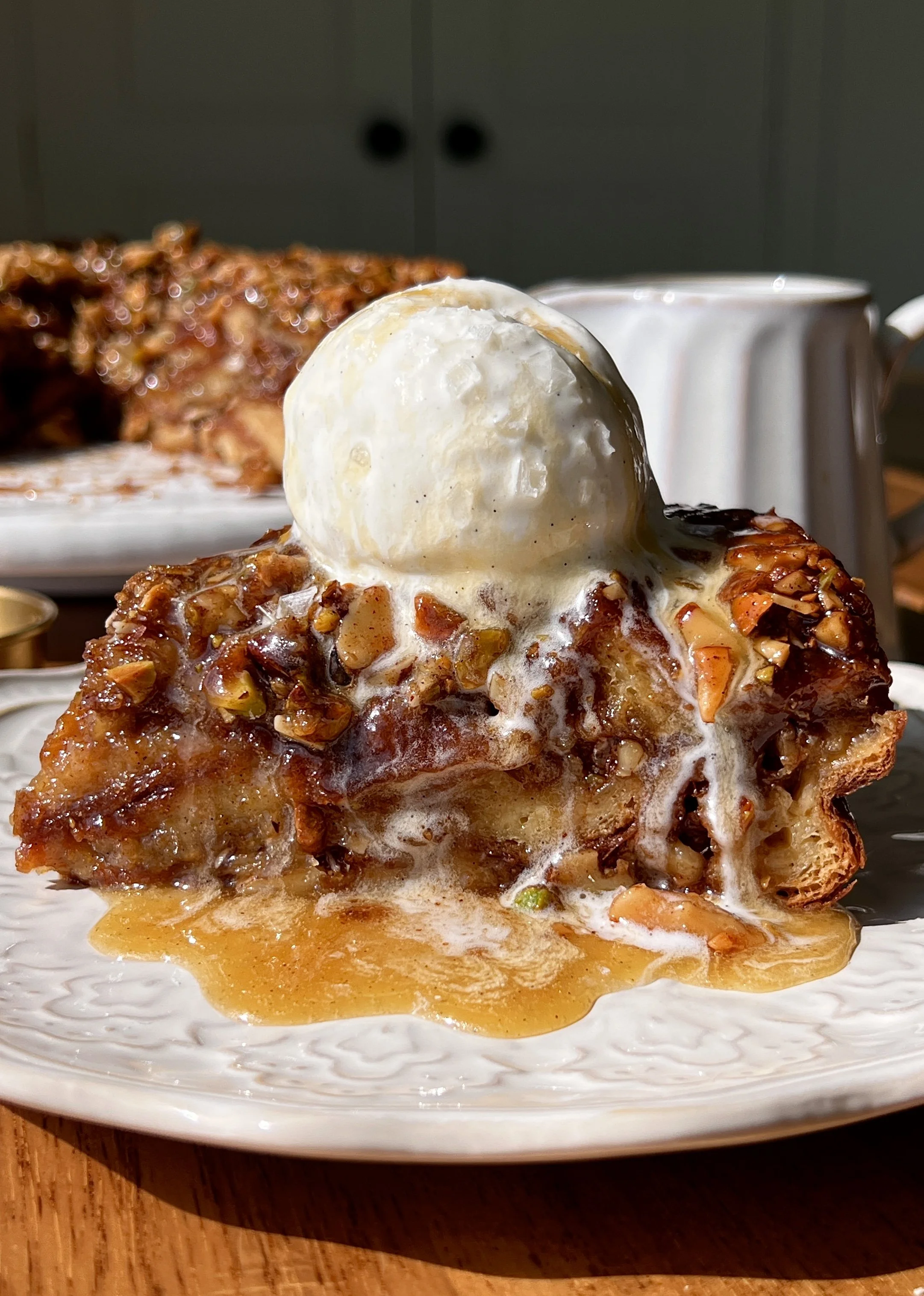 Baklava croissant bread pudding baked until golden and served warm with a scoop of vanilla ice cream, a drizzle of honey buttermilk syrup, and flaky sea salt.