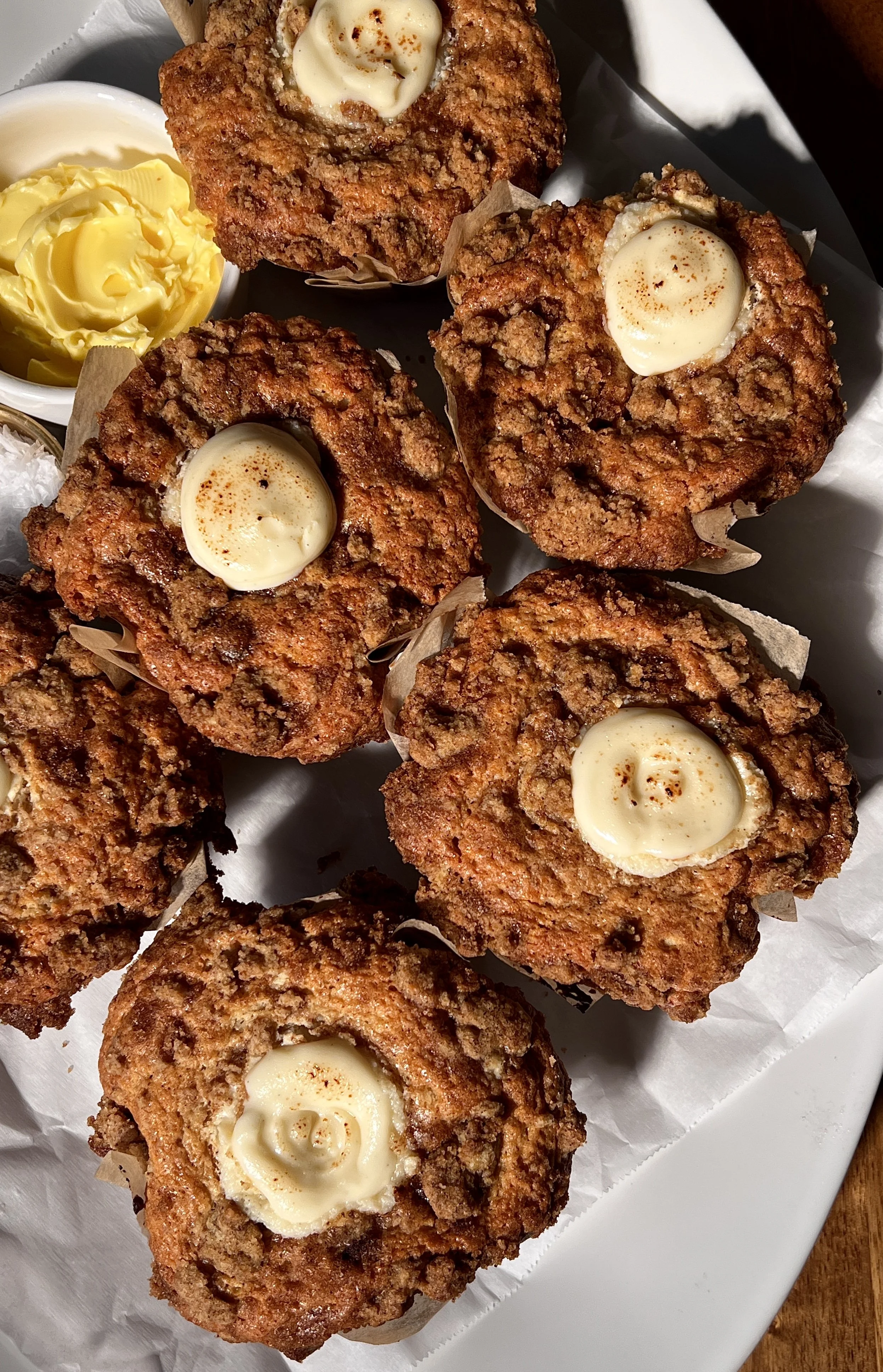 Brown butter cinnamon roll cream cheese muffins with a tender crumb, cinnamon swirl throughout, and a crumb topping, served warm with a cup of coffee.