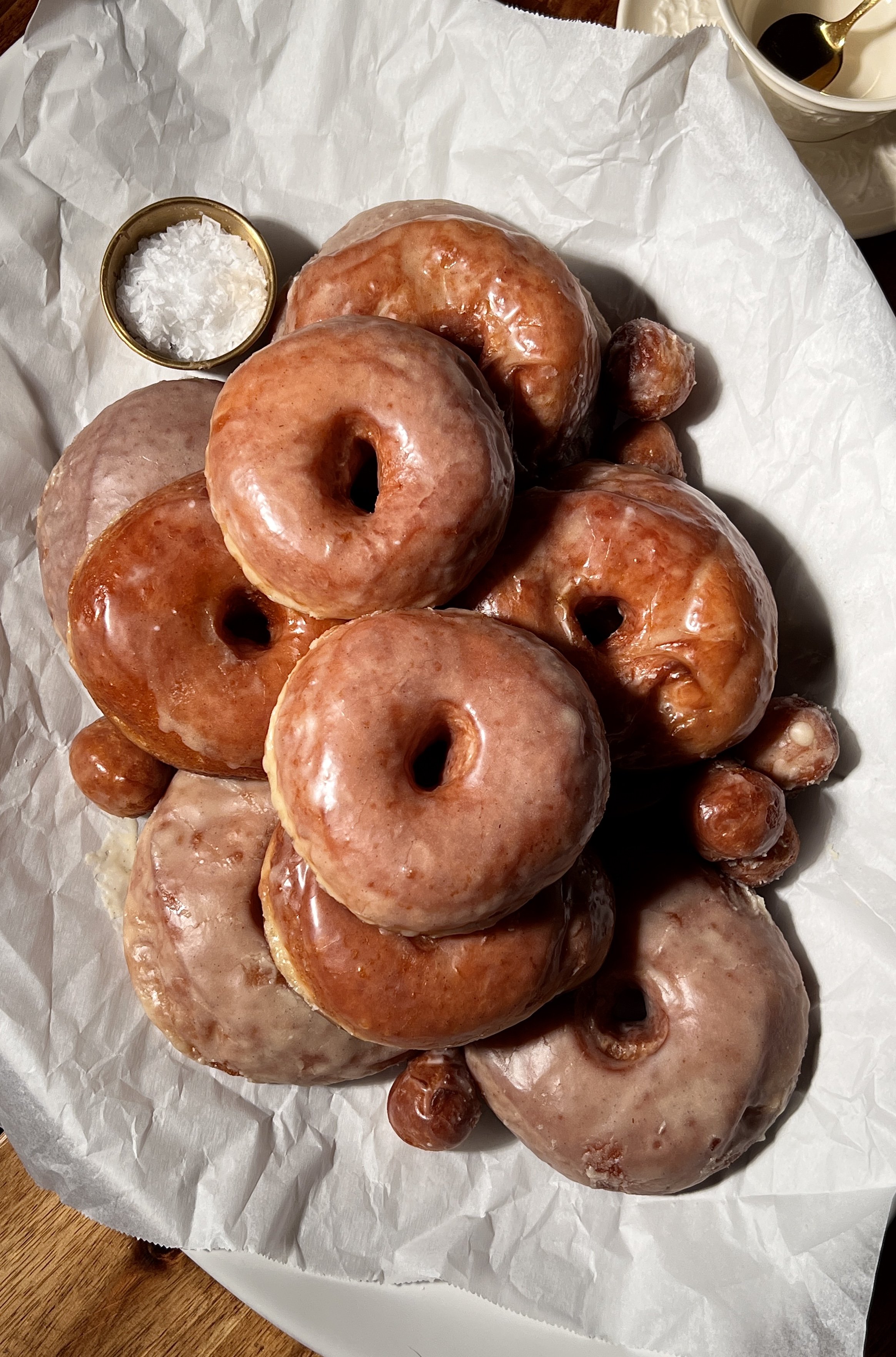 Classic vanilla bean glazed donuts served warm, showing a golden exterior and soft, pillowy interior, coated in a crackly vanilla bean glaze with coffee on the side.